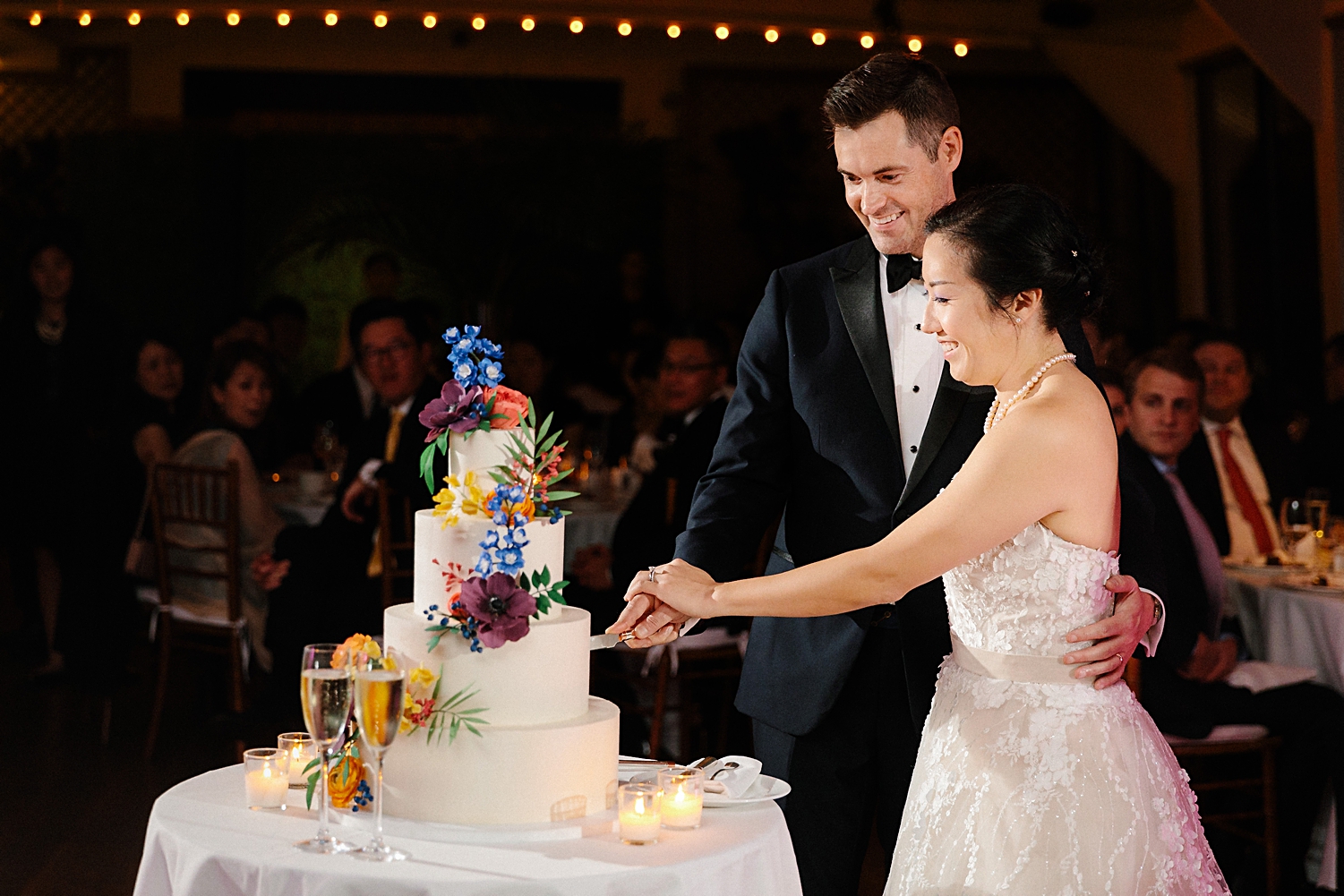 bride and groom cutting colorful three tiered wedding cake