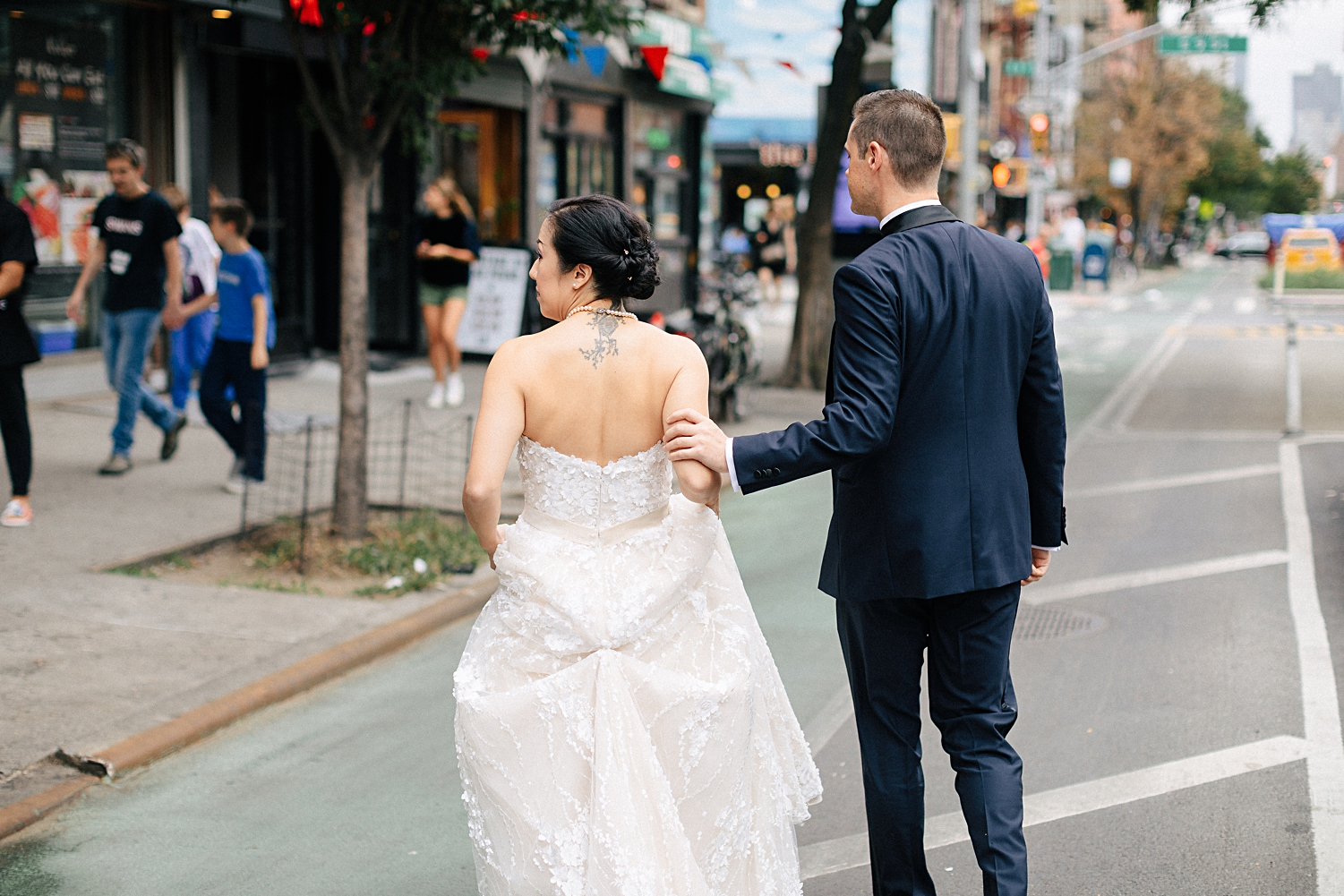 groom in navy suite helping bride down the street in new york city