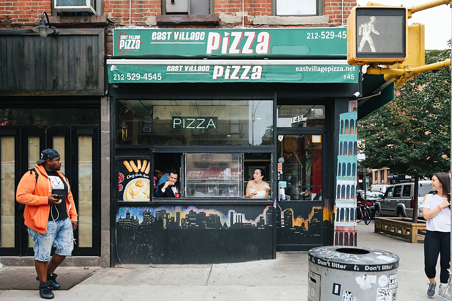 bride and groom eating pizza in new york city pizzeria window