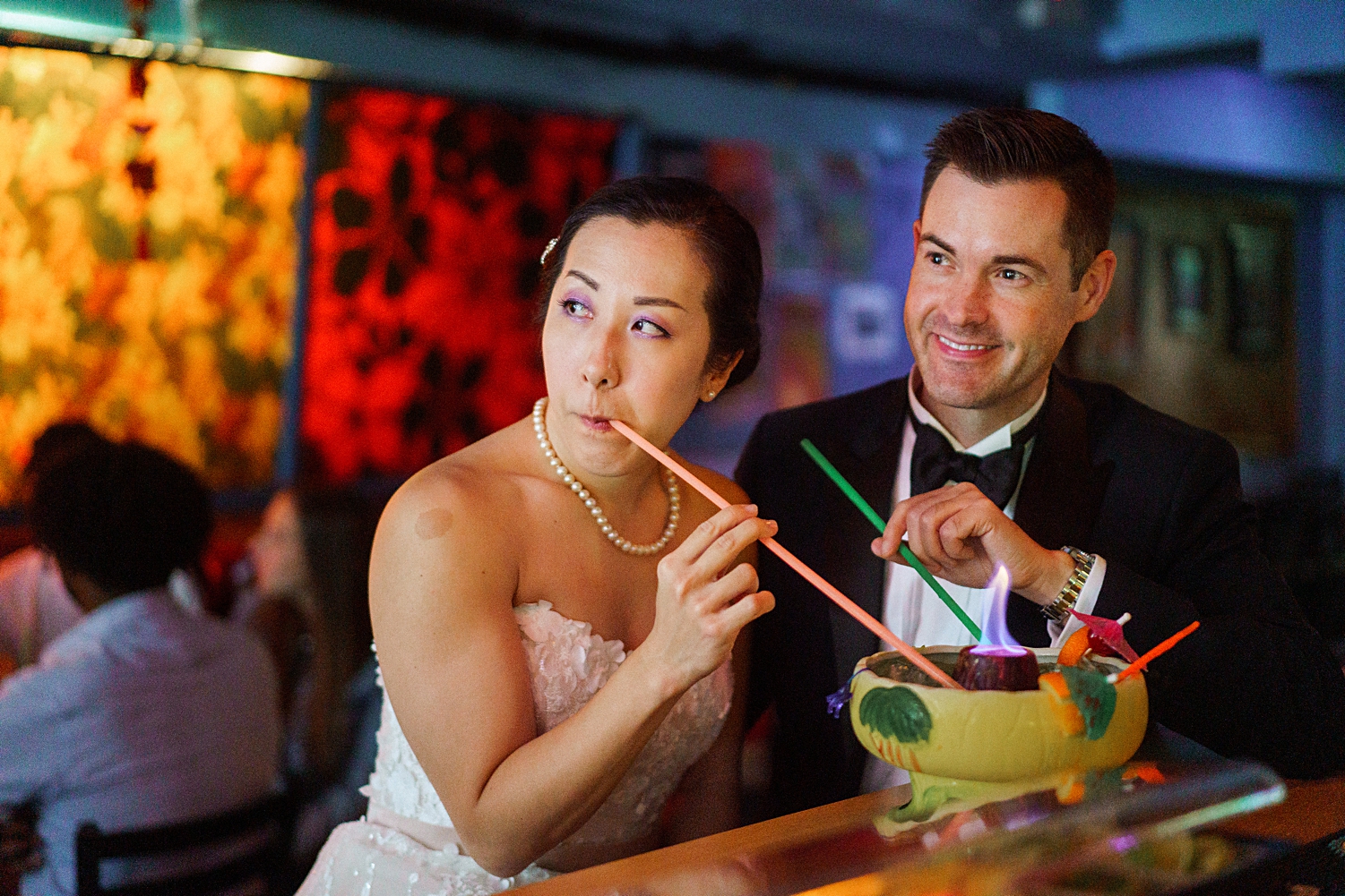 bride and groom sitting and sipping from straws at tiki bar  in new york city