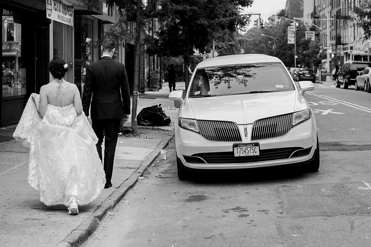 bride and groom walking toward white limo