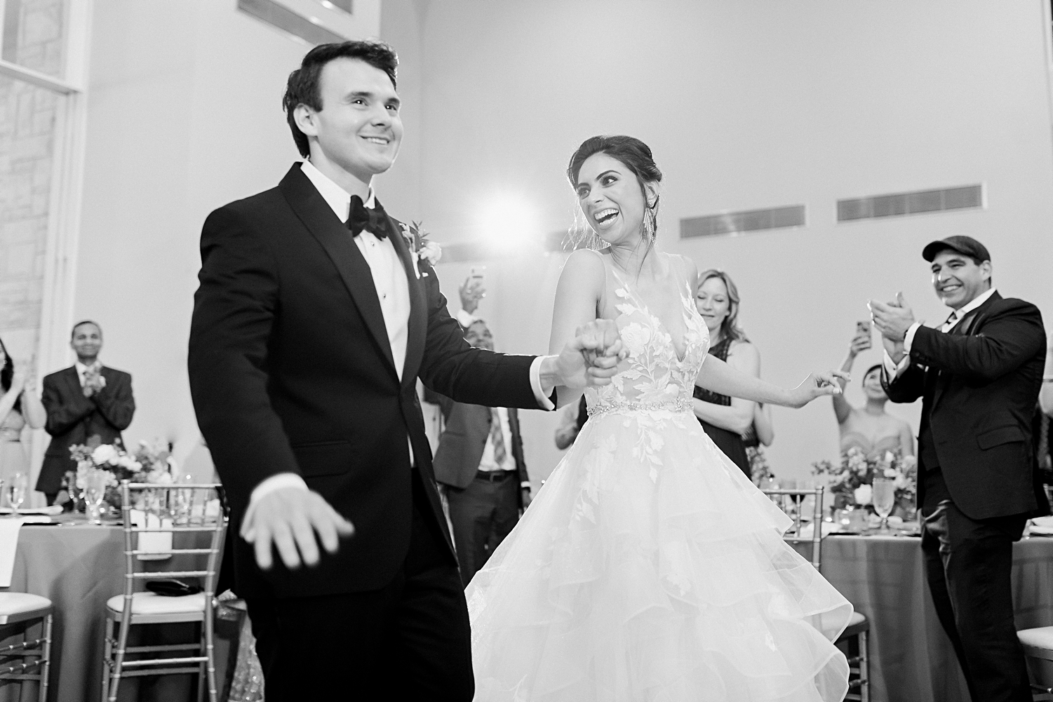 bride and groom dancing into wedding reception smiling black and white