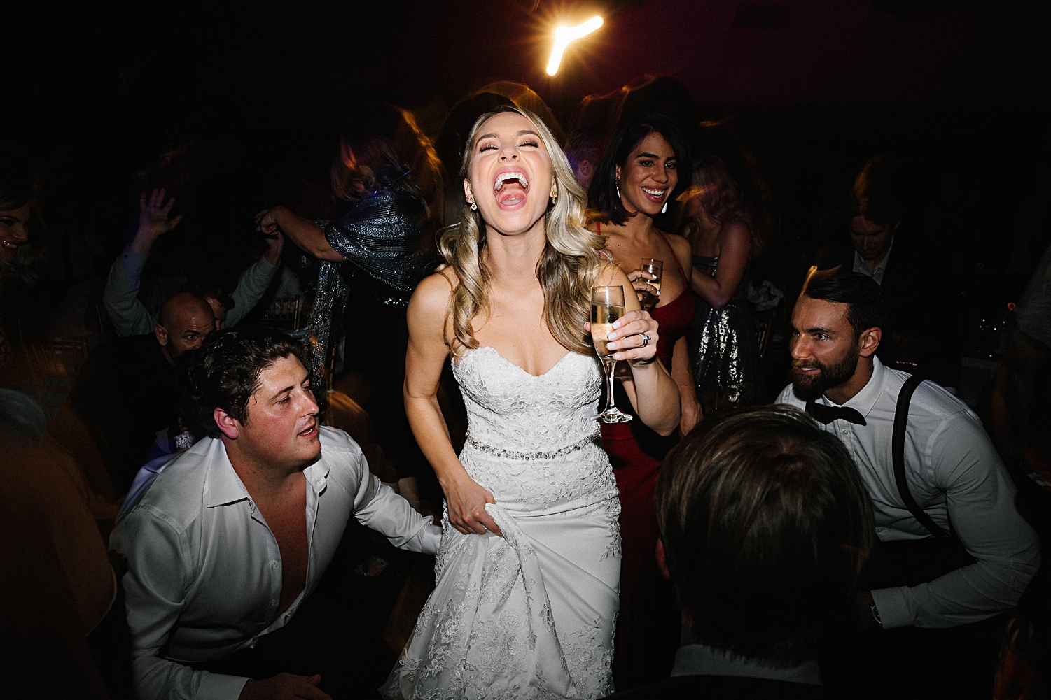 bride holding champagne laughing on dance floor