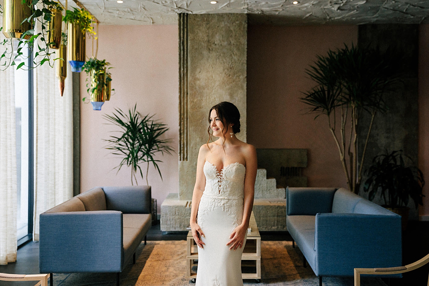 Bride standing in front of pink wall blue sofas concrete fireplace Line Hotel Austin wedding venues