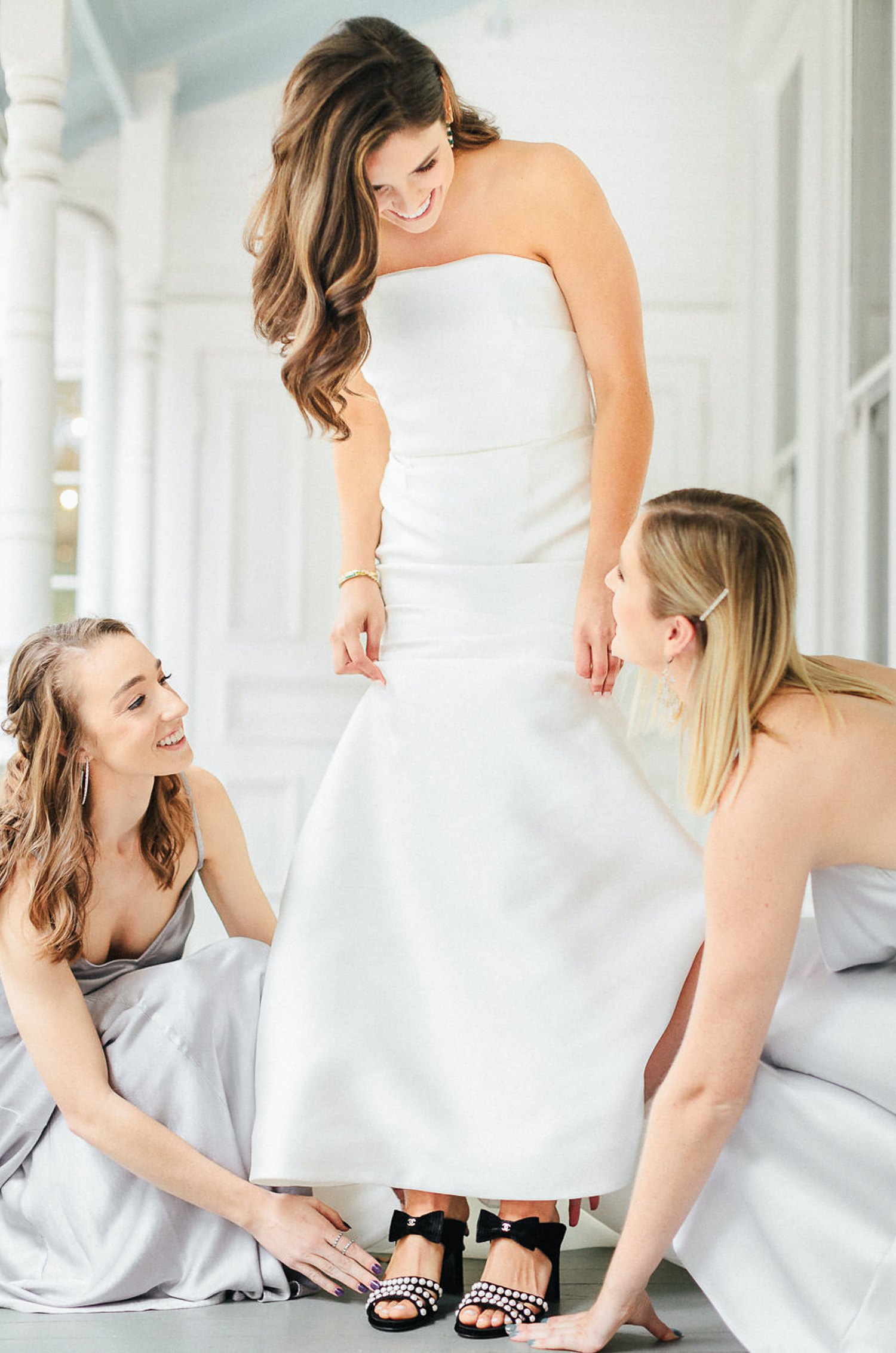 bride and bridesmaids putting on shoes white wedding dress