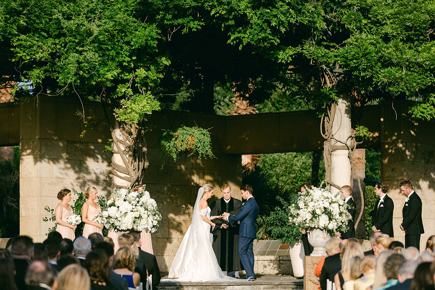 Bride and groom exchanging rings at ceremony altar Dallas Arboretum wedding