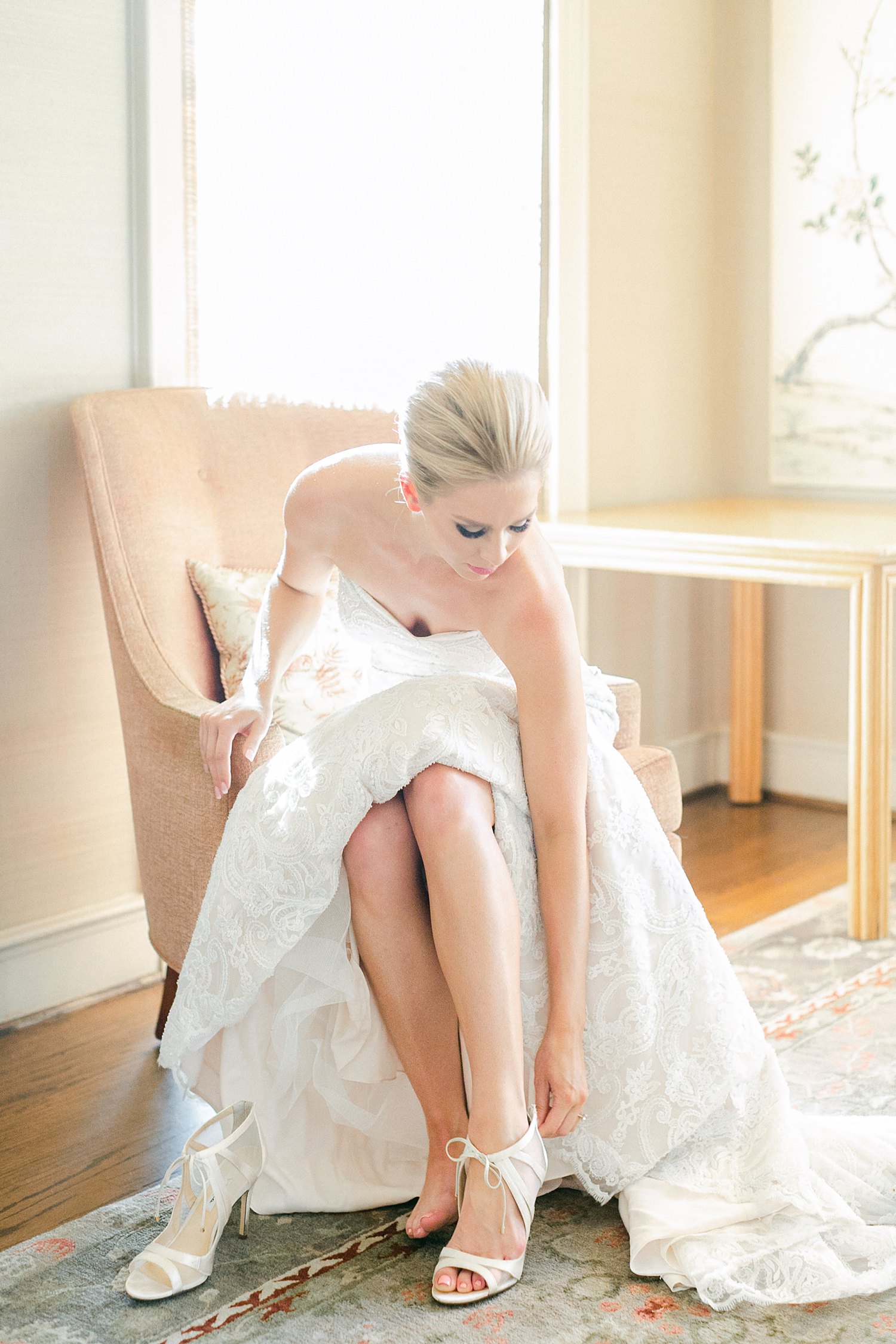 Bride sitting putting on white high heel shoes