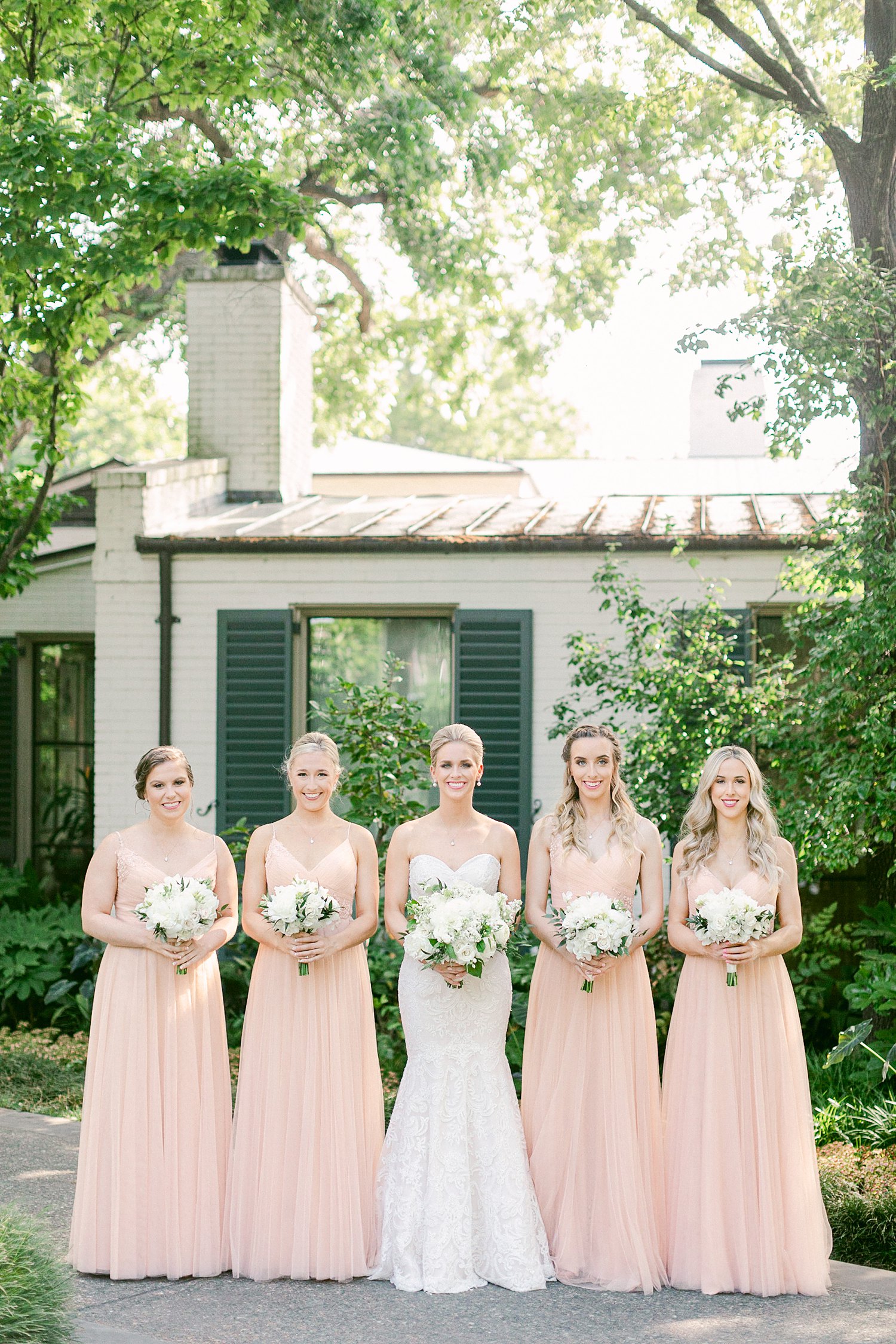 Bride holding white bouquet with four bridesmaids at Dallas Arboretum Wedding