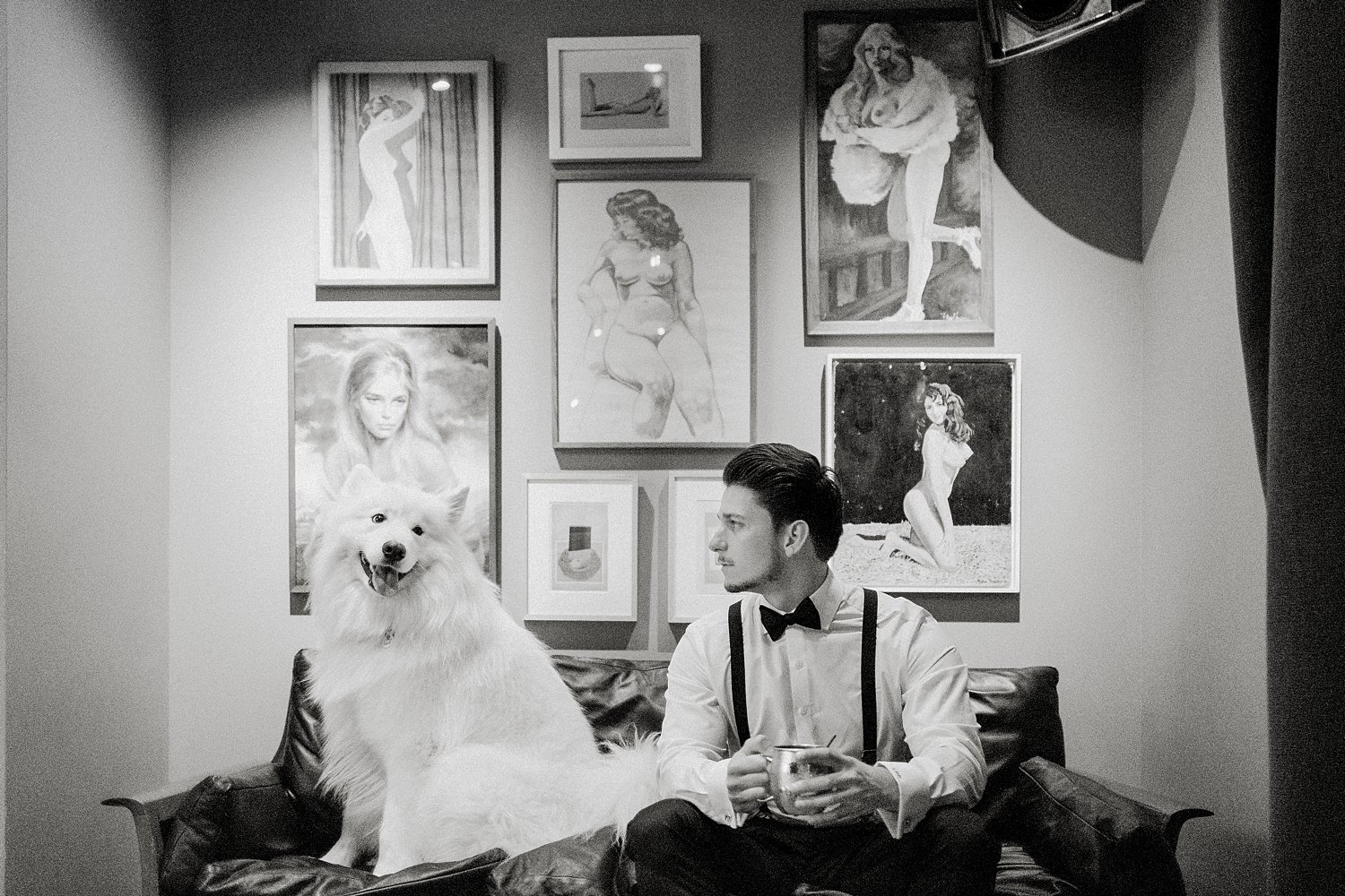 Man sitting with white fluffy dog in front of gallery wall black and white