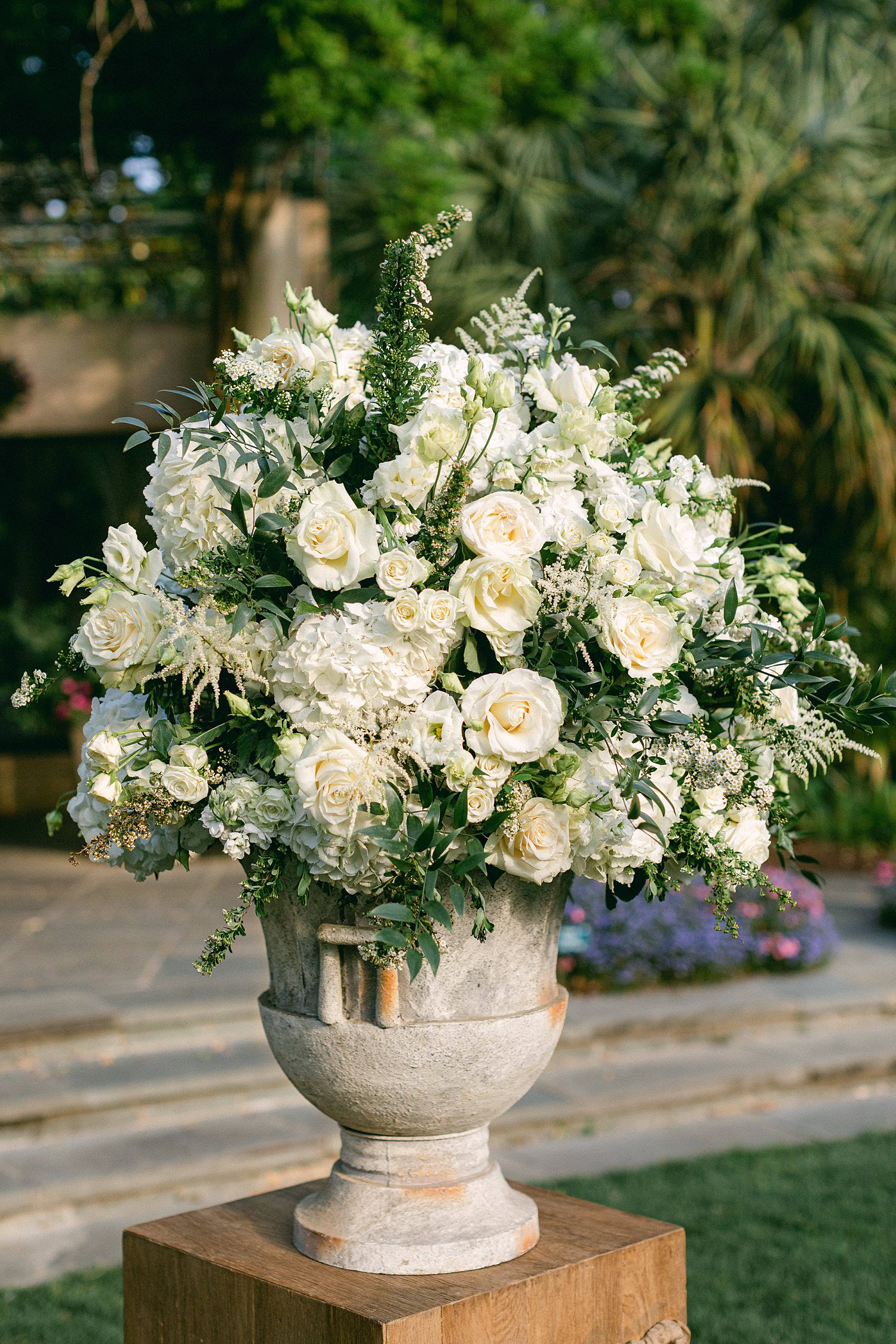 White flowers in large vase sitting outside at wedding ceremony garden