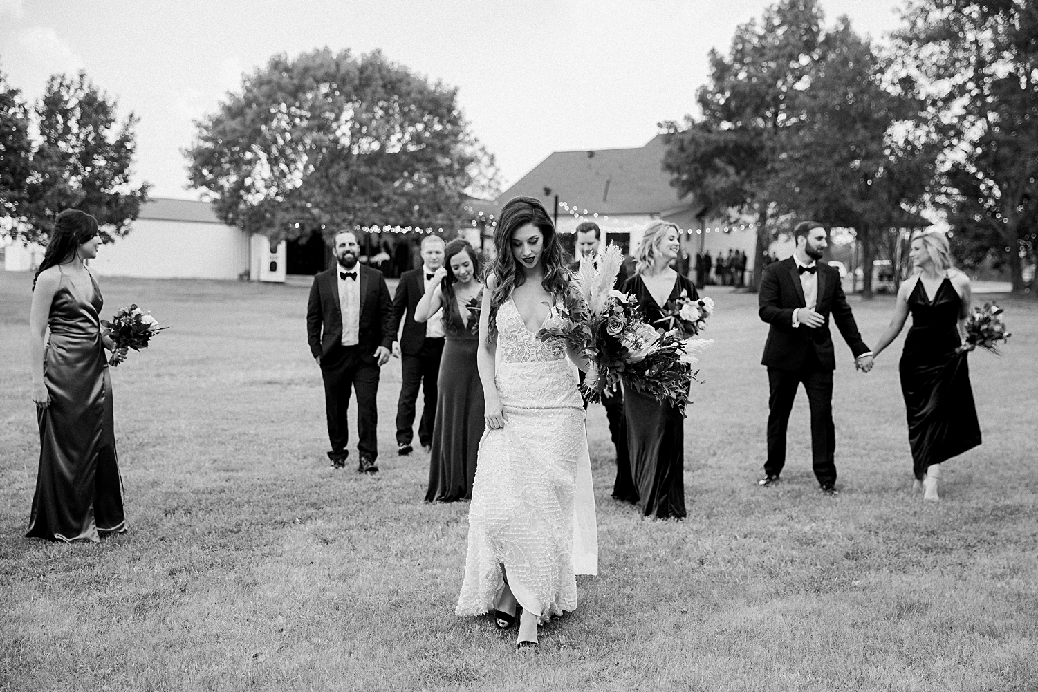 bridal wedding party walking in grass field black and white