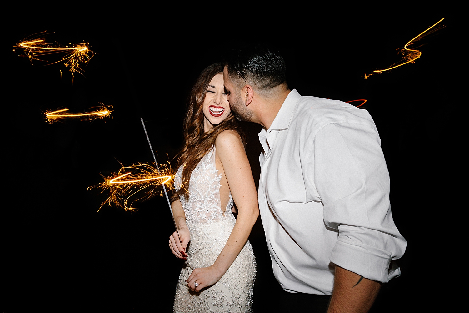 bride and groom smiling sparkler holding night