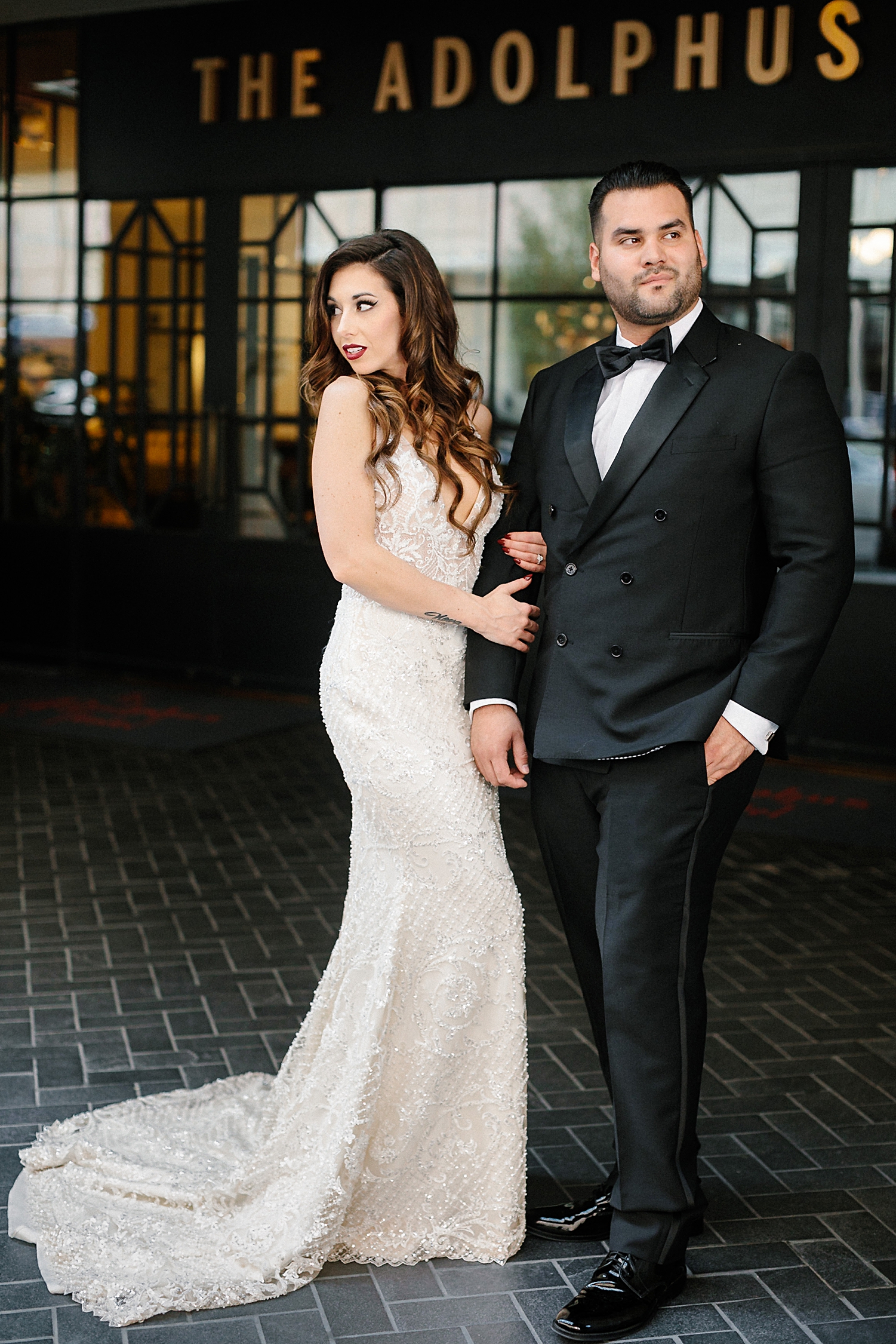 bride in wedding dress and groom in double breasted tuxedo standing together outside adolphus hotel Dallas