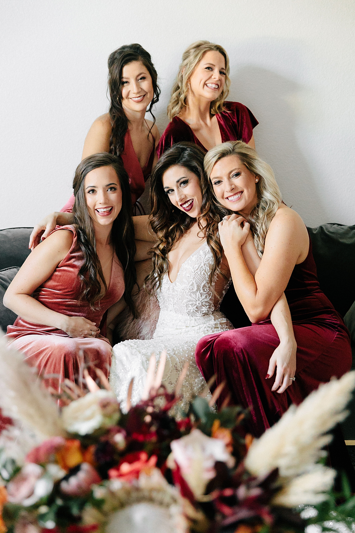 bride surrounded by bridesmaids in red Jenny Yoo dresses smiling Emerson Venue Wedding