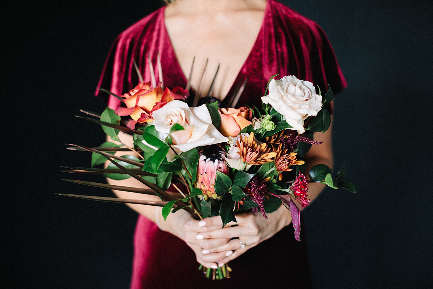 bridesmaid with large boho bouquet red velvet dress black background