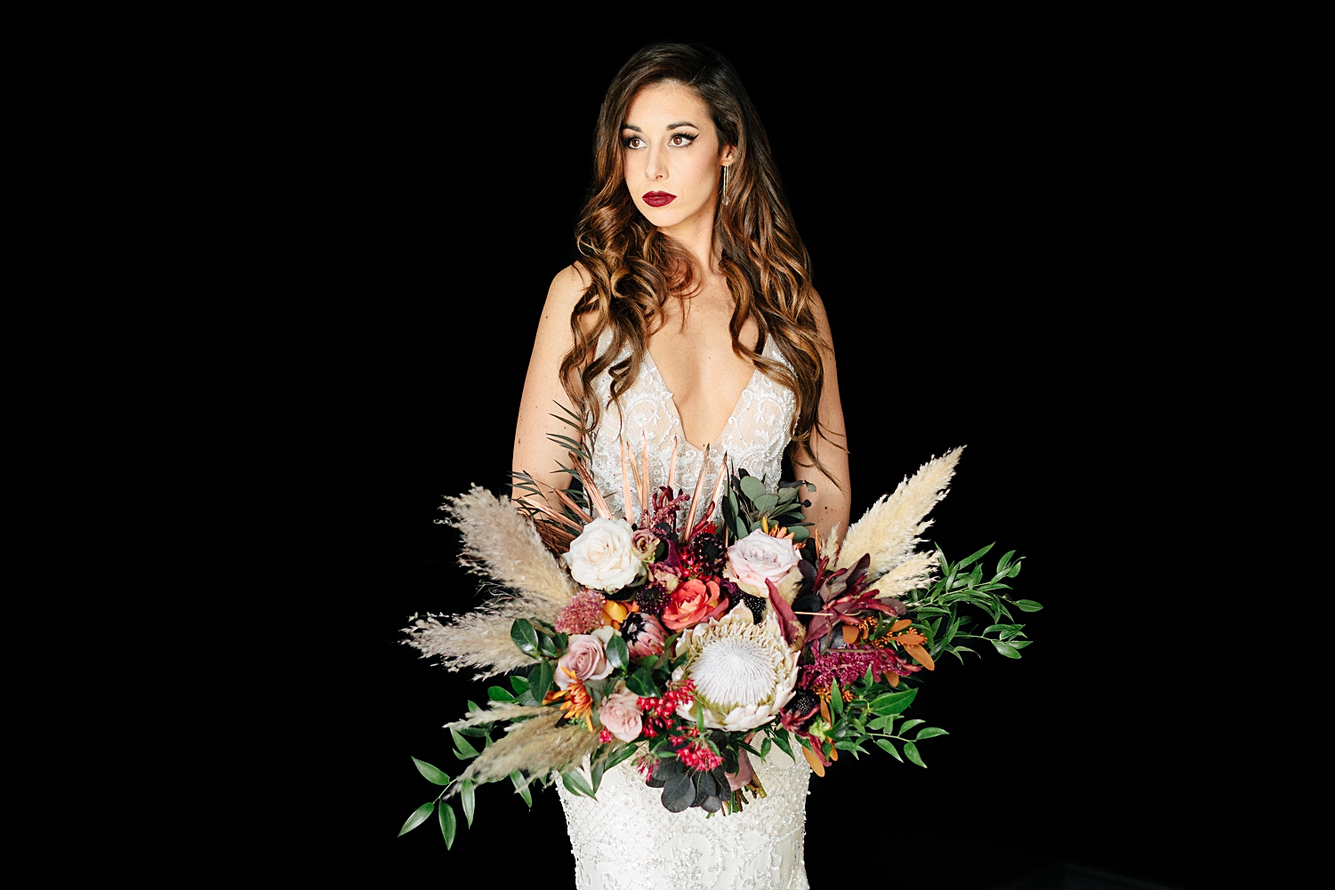 bride with large boho bouquet wedding black background
