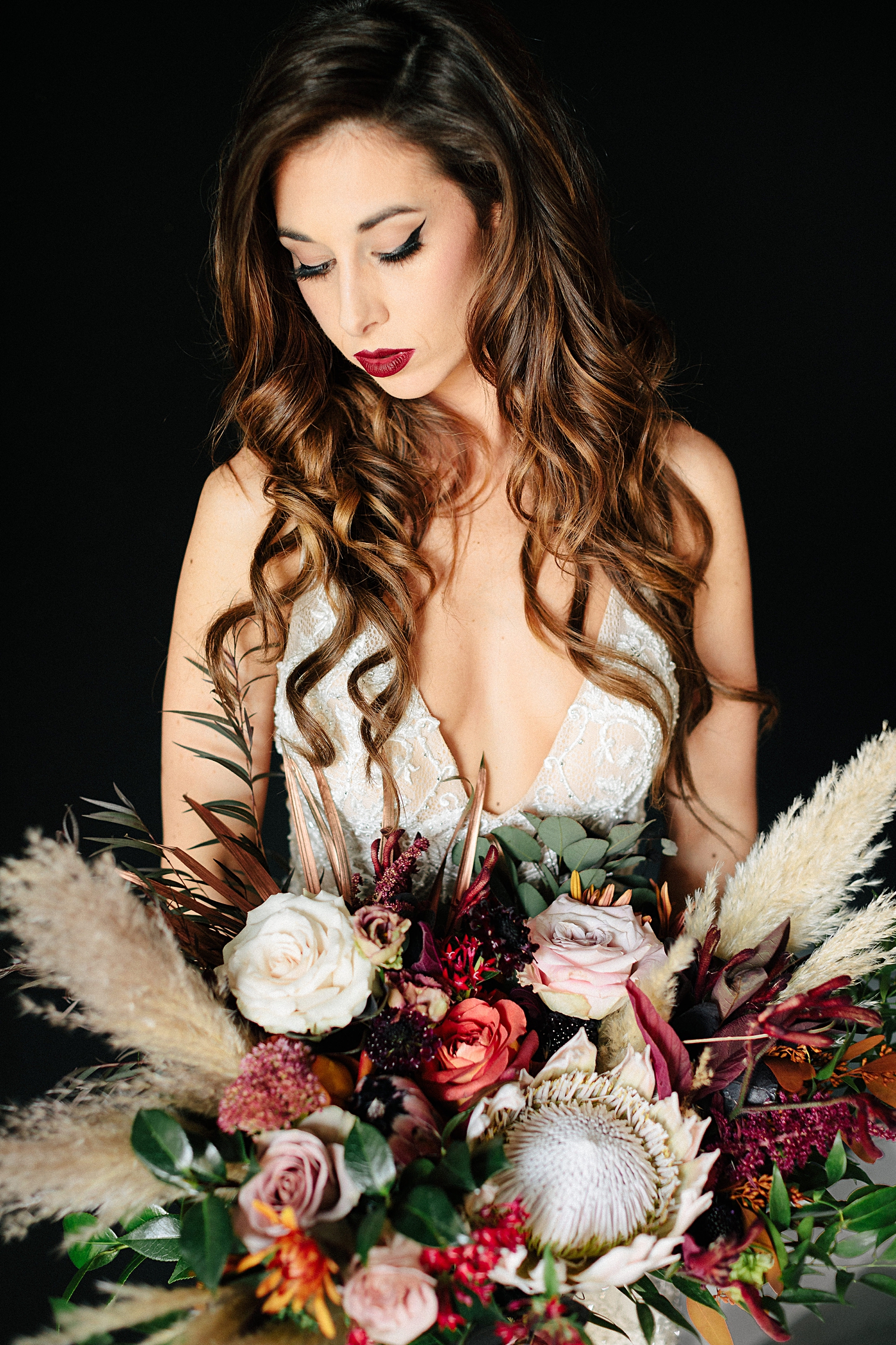 bride in white dress with large boho bouquet black background Emerson Venue Wedding