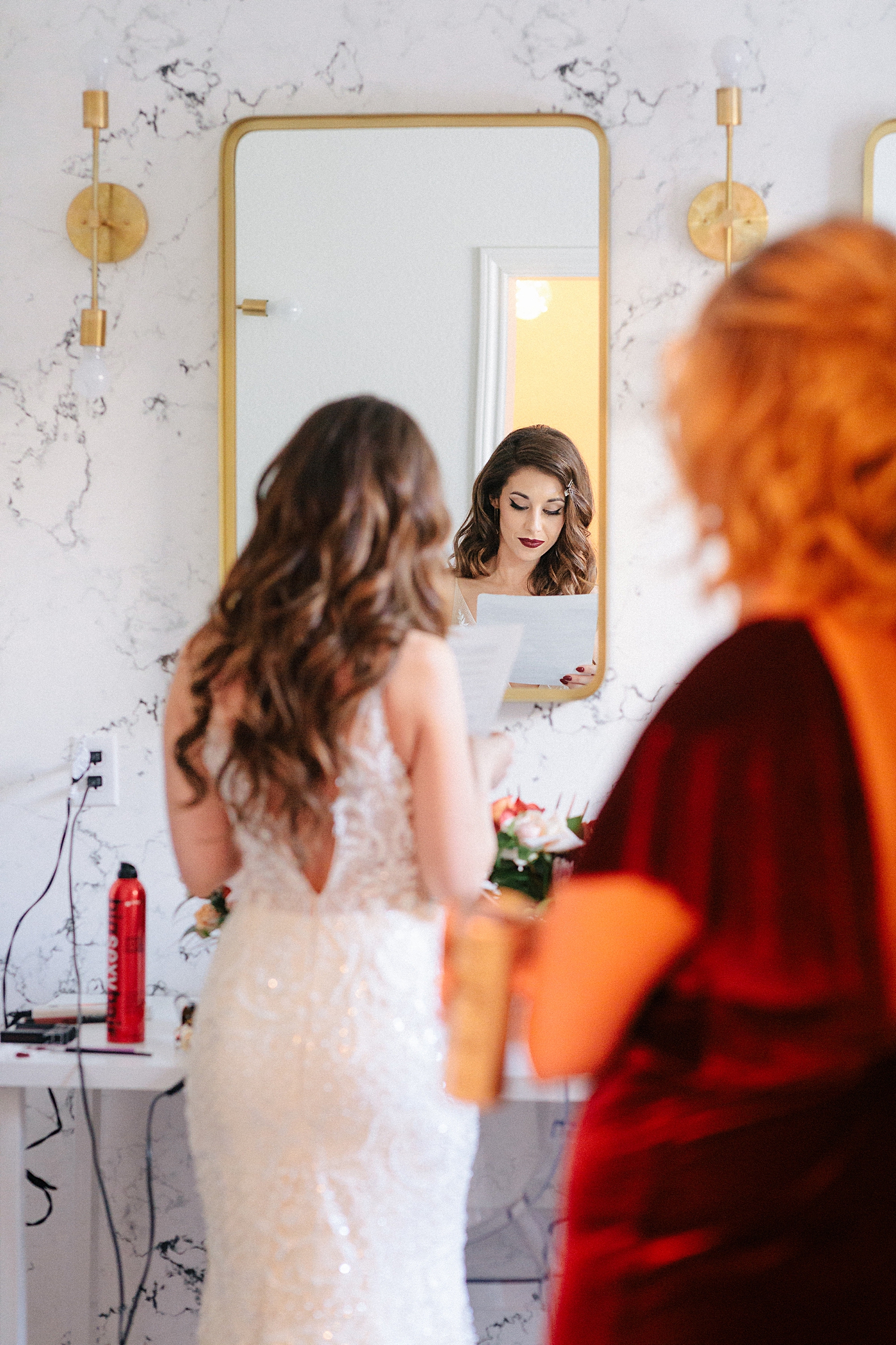 bride looking at paper in mirror wedding dress