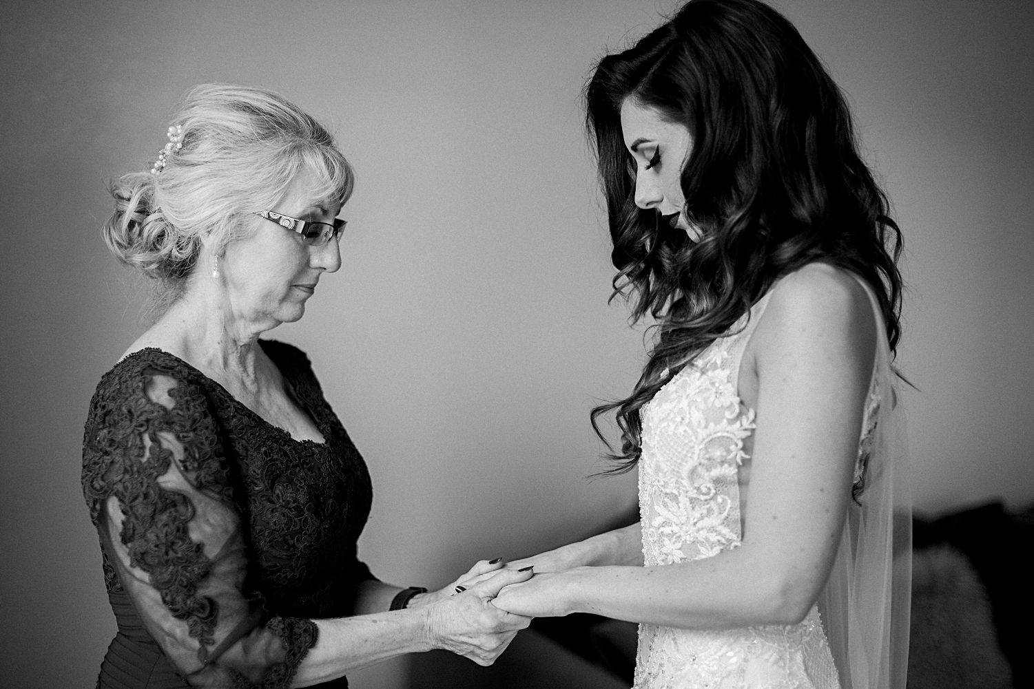 mother holding hands with bride in wedding dress