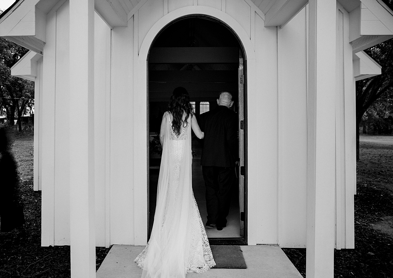 back of father and bride entering doorway white chapel wedding
