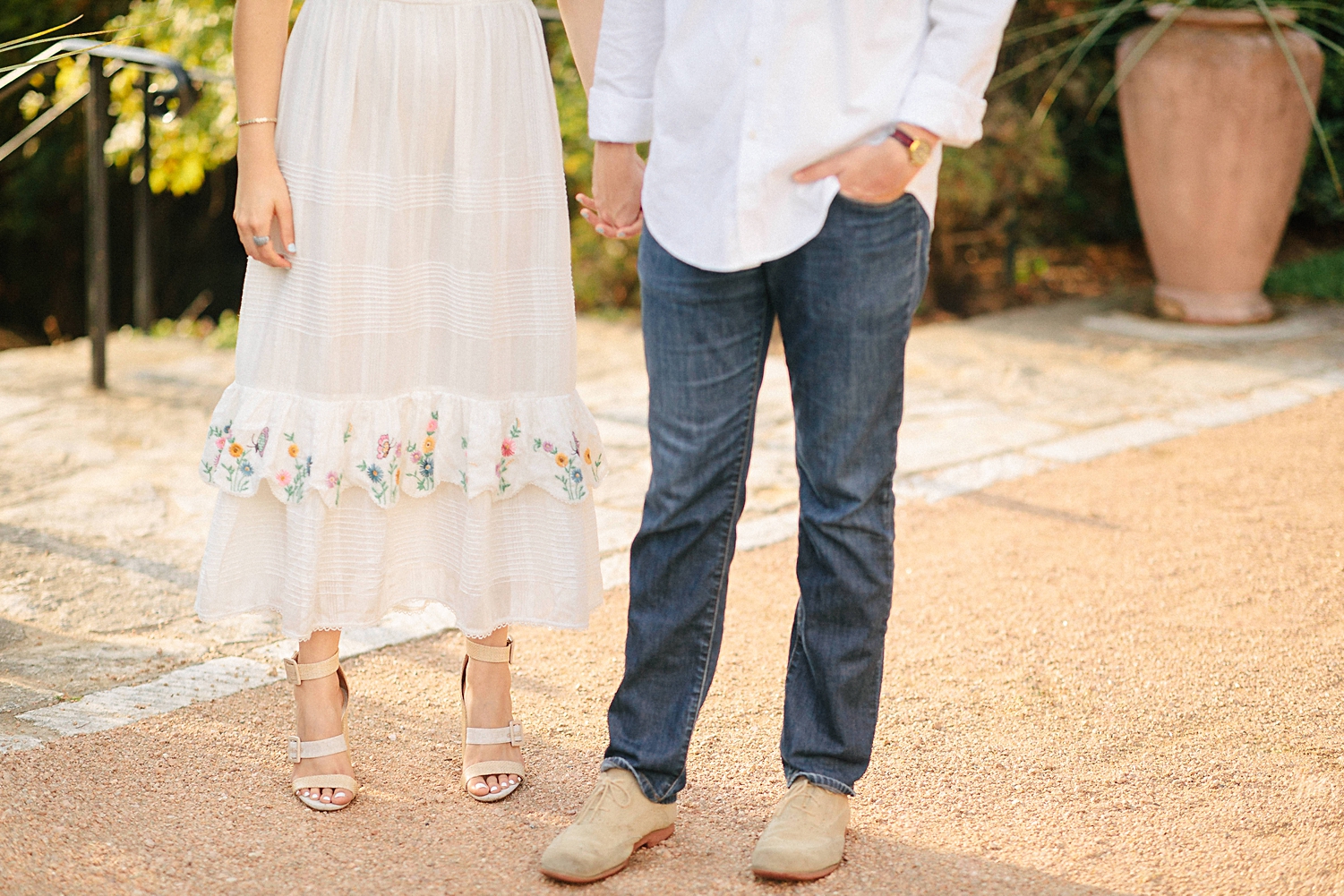 legs of boy in white shirt holding hands with girl in white dress