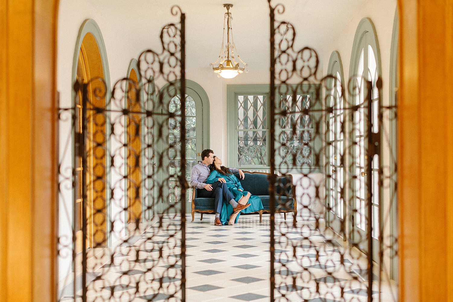 couple sitting on blue couch in spanish revival laguna gloria room green windows blue dress