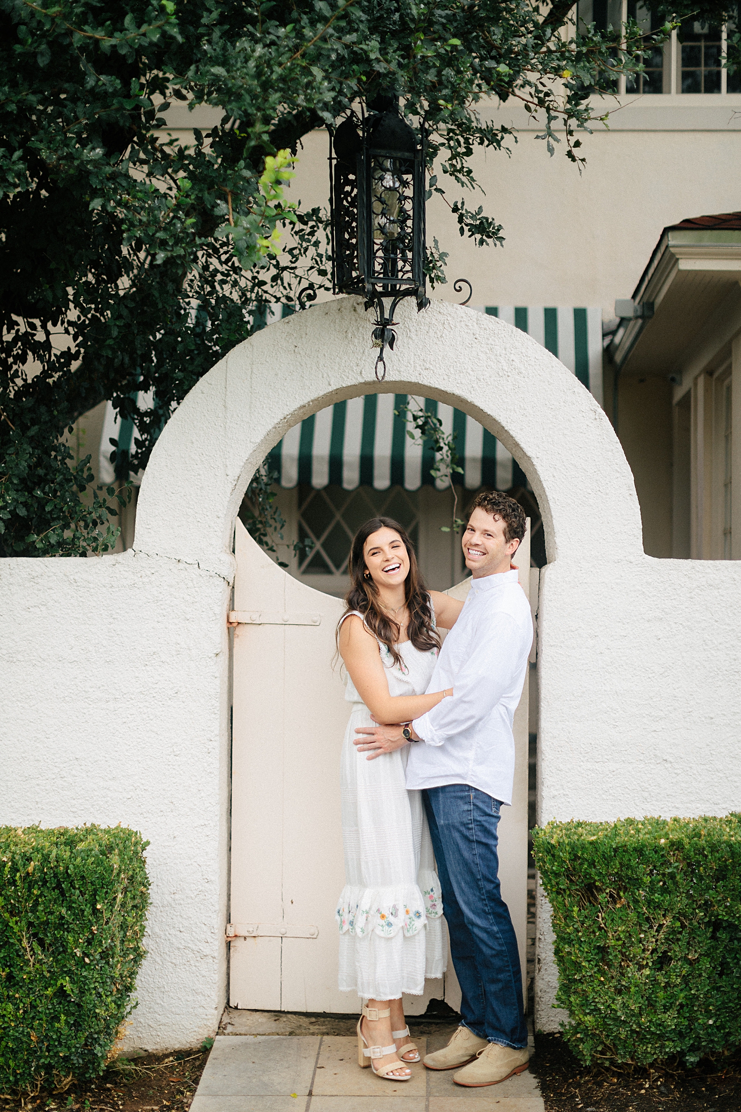 Laguna Gloria Austin white spanish building couple laughing in front of gate