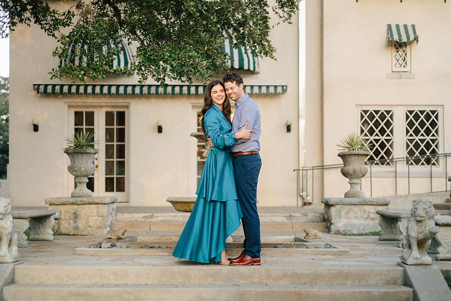 woman in blue dress laughing with man in front of Spanish mansion laguna gloria austin 
