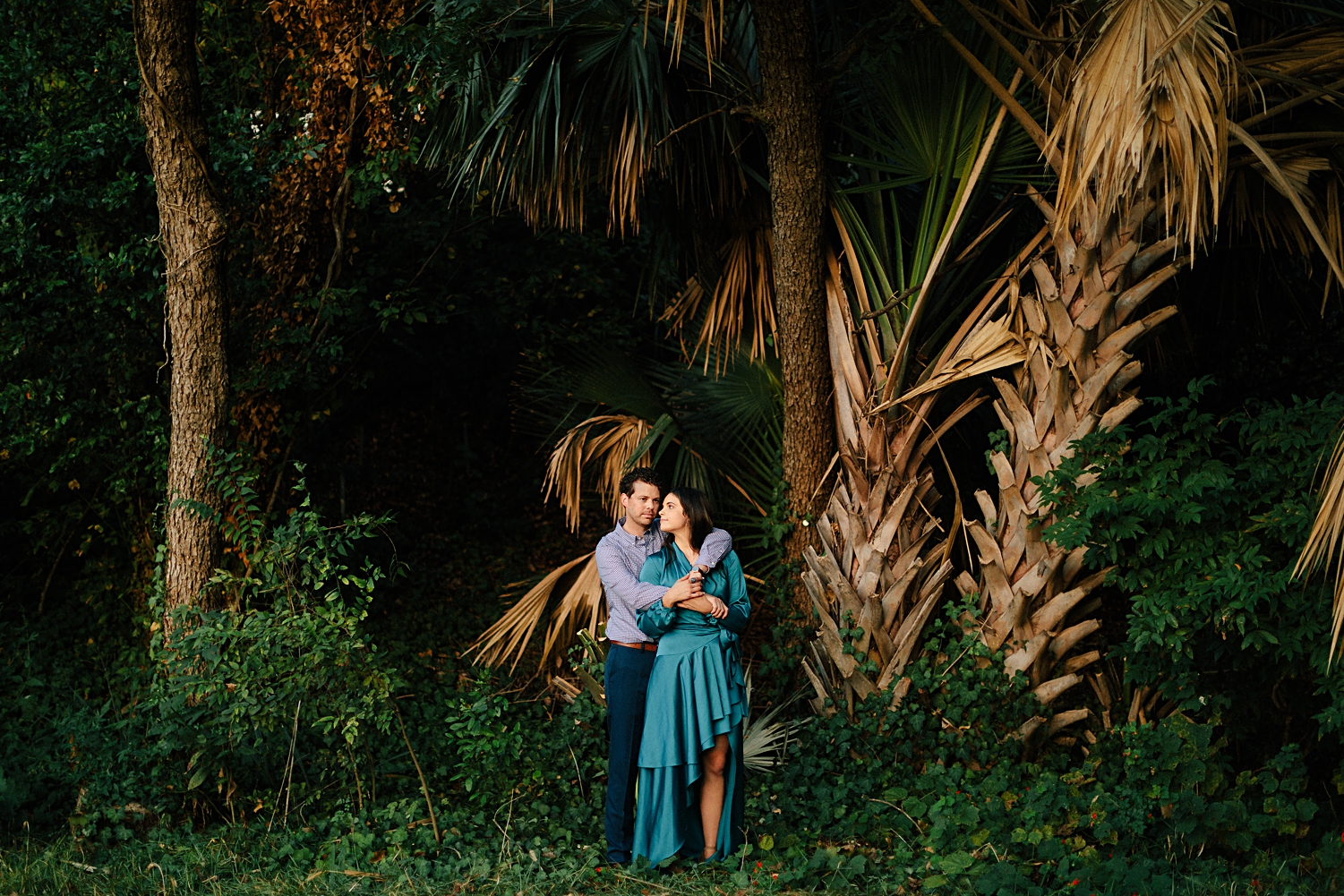 boy holding hands with girl in dress in laguna gloria green tropical garden