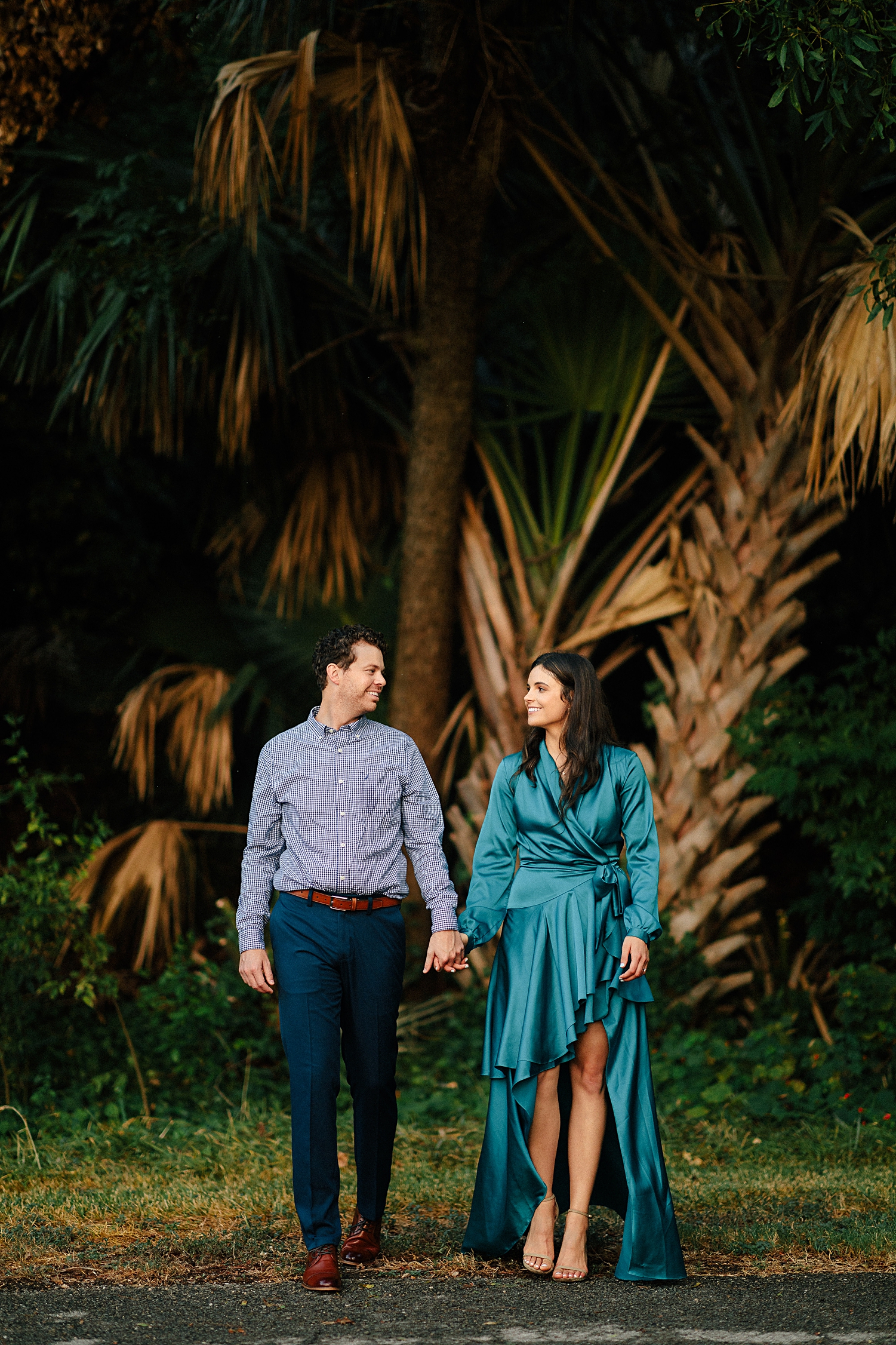 boy holding hands with girl in dress in laguna gloria tropical garden