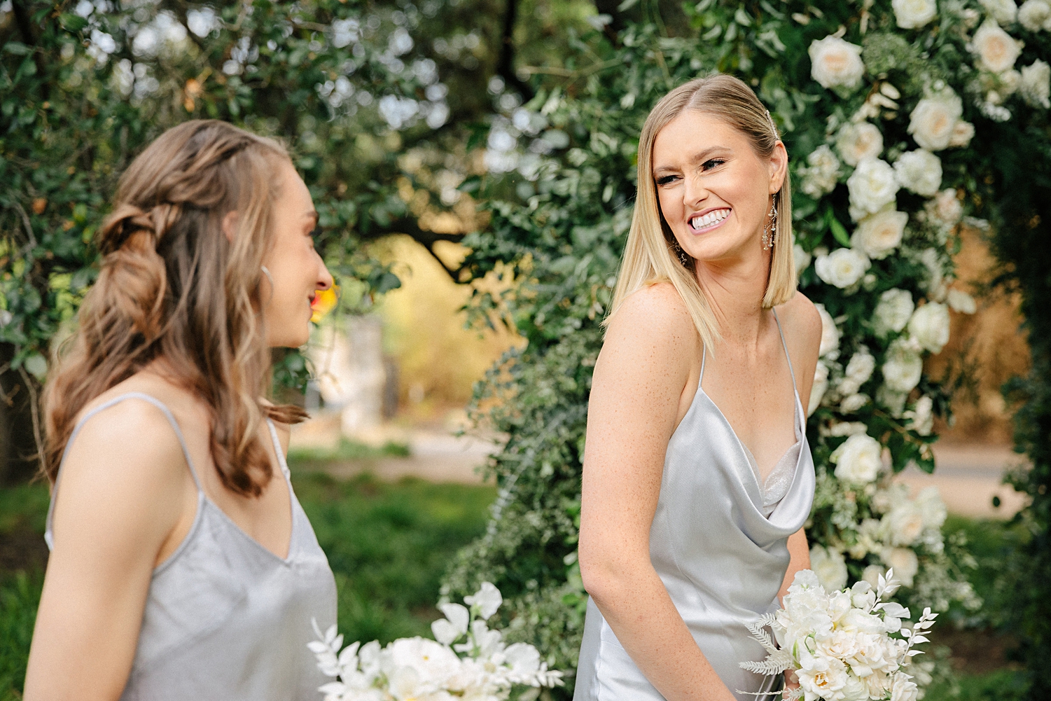 bridesmaid in silver dress holding white bouquet smiling at garden matties wedding austin