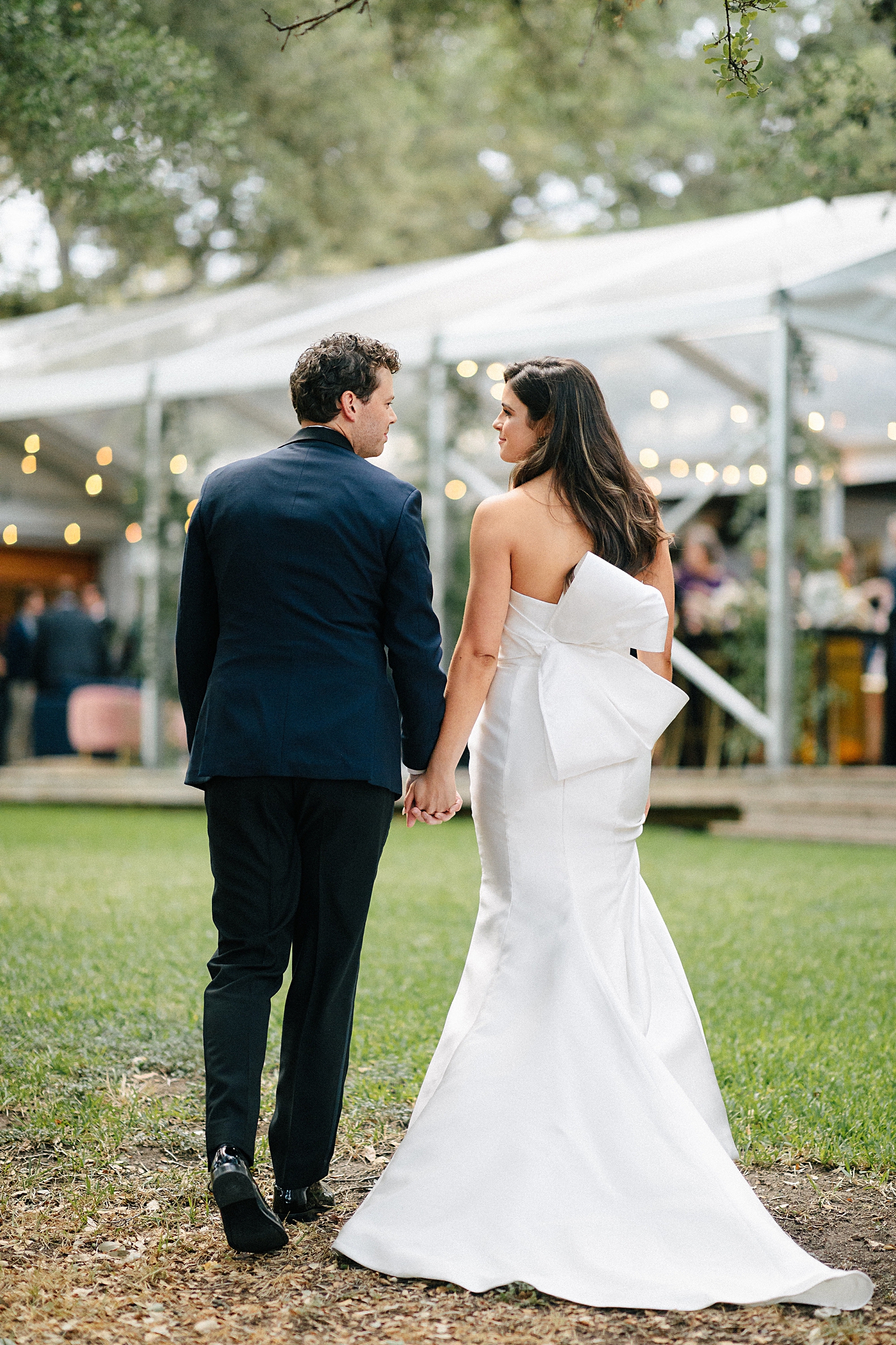 Groom in navy suit walking with bride in white strapless wedding dress
