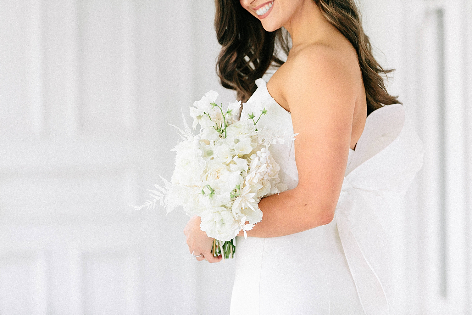 bride in strapless wedding dress with bow standing with white bouquet at Mattie's Austin