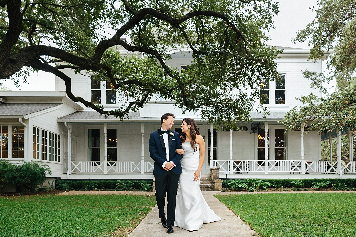 Bride and Groom walking in front of white southern mansion Mattie's At Green Pastures Wedding Austin