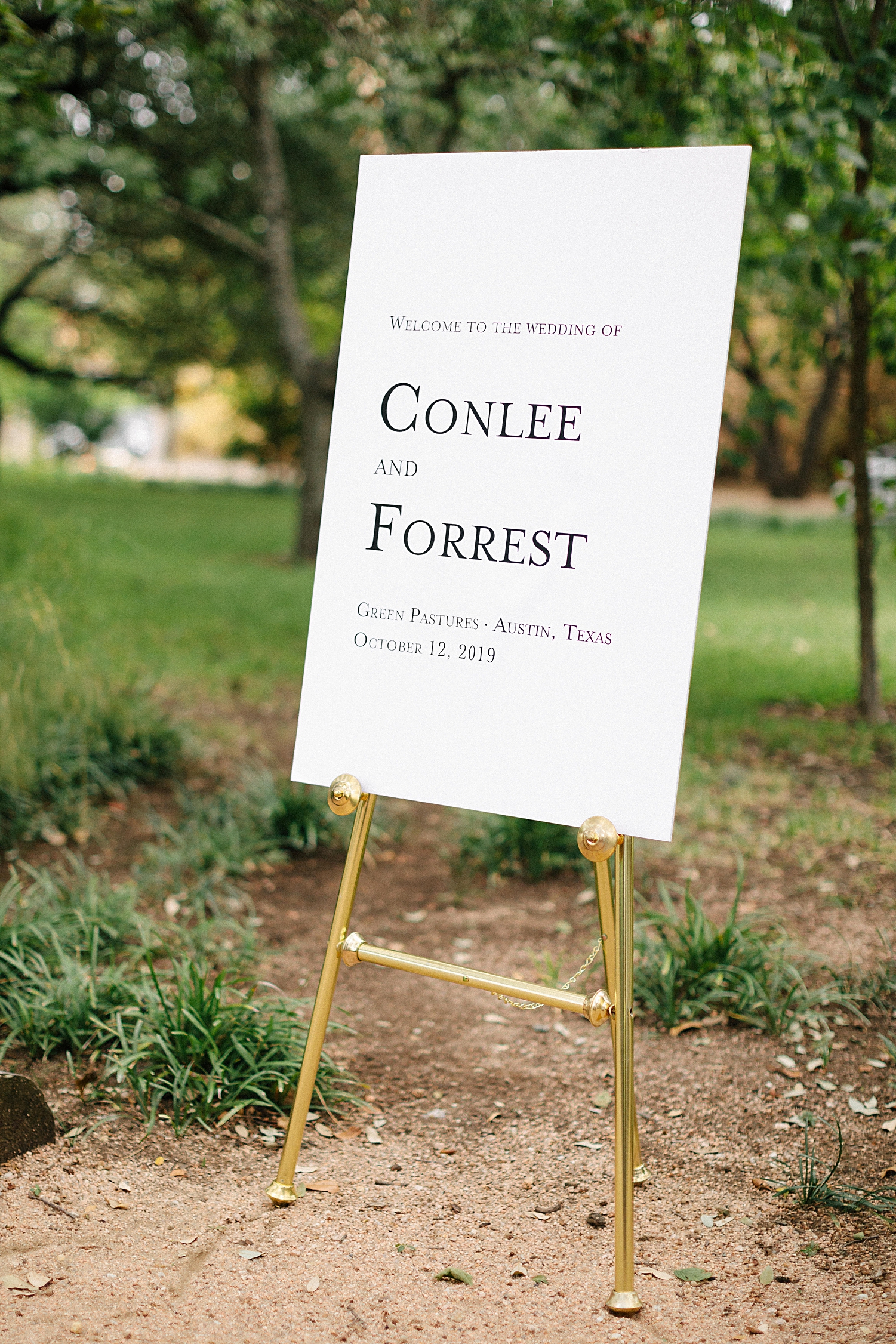 white welcome wedding sign on gold stand 