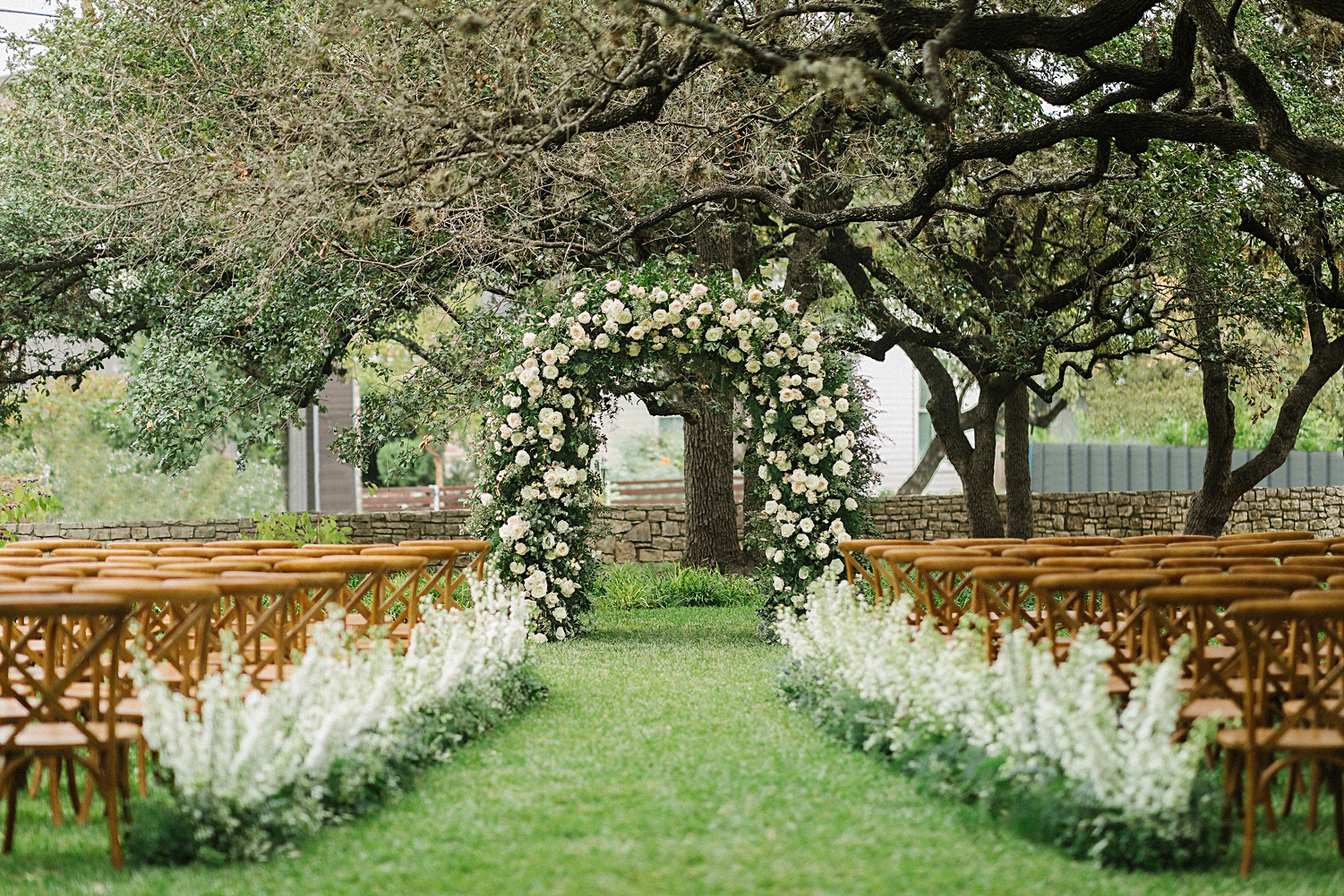 garden ceremony design altar Mattie's At Green Pastures Austin wedding Venue trees white flower arch brown chairs