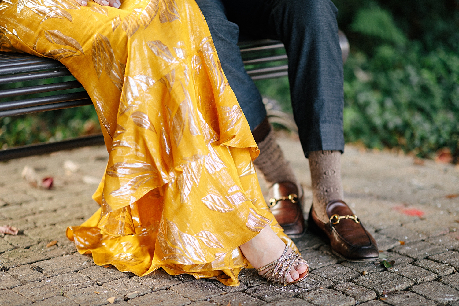shoes on feet of man and woman in yellow dress sitting on park bench