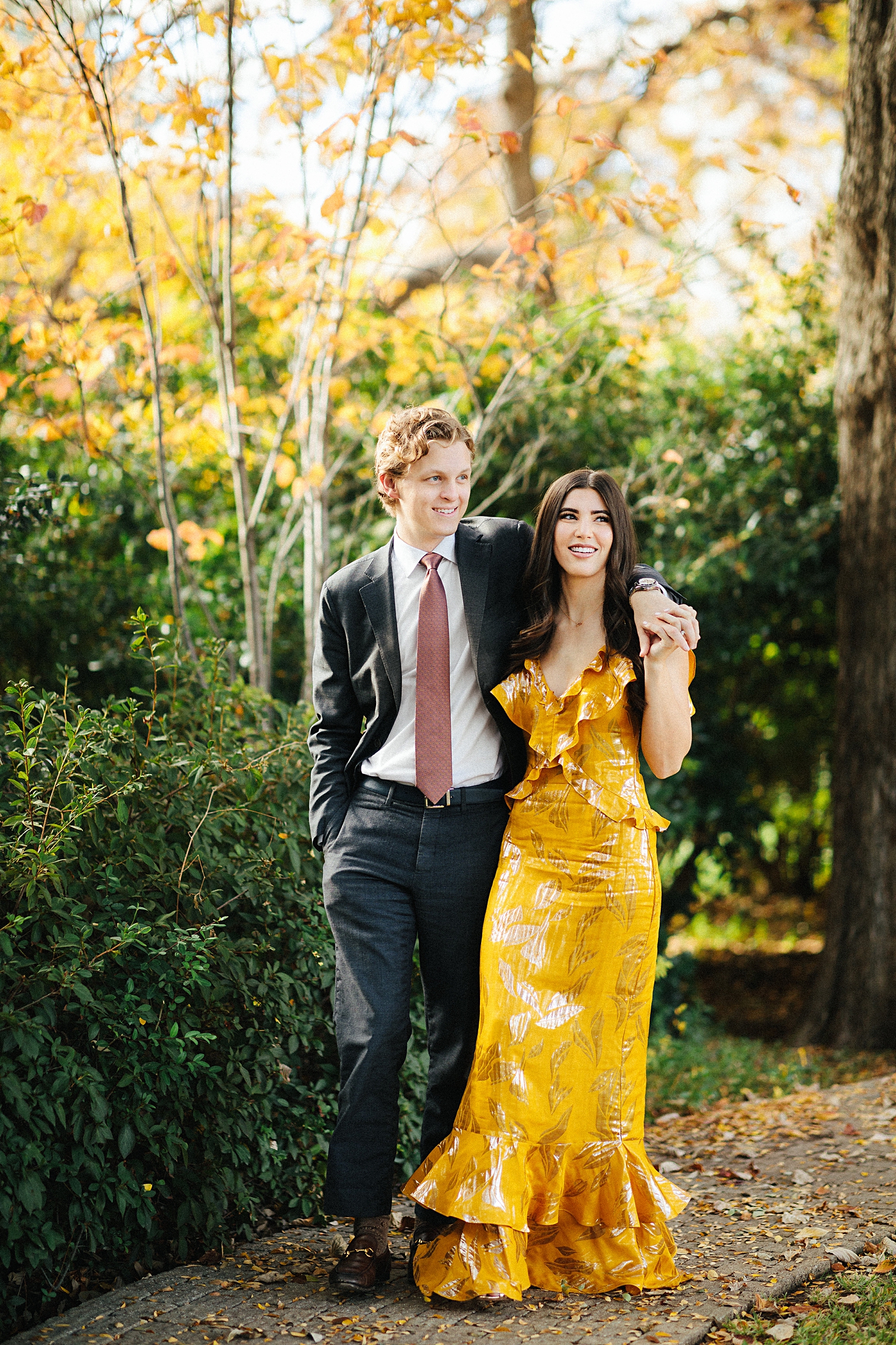 brunette girl in yellow dress walking with man in suit arm in arm
