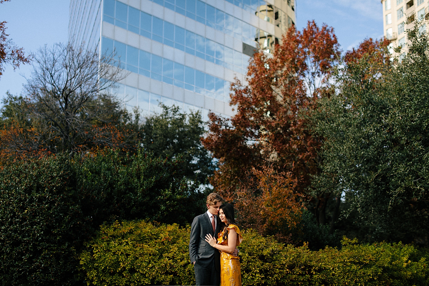 woman in yellow dress standing with man in suit in turtle creek park dallas engagement