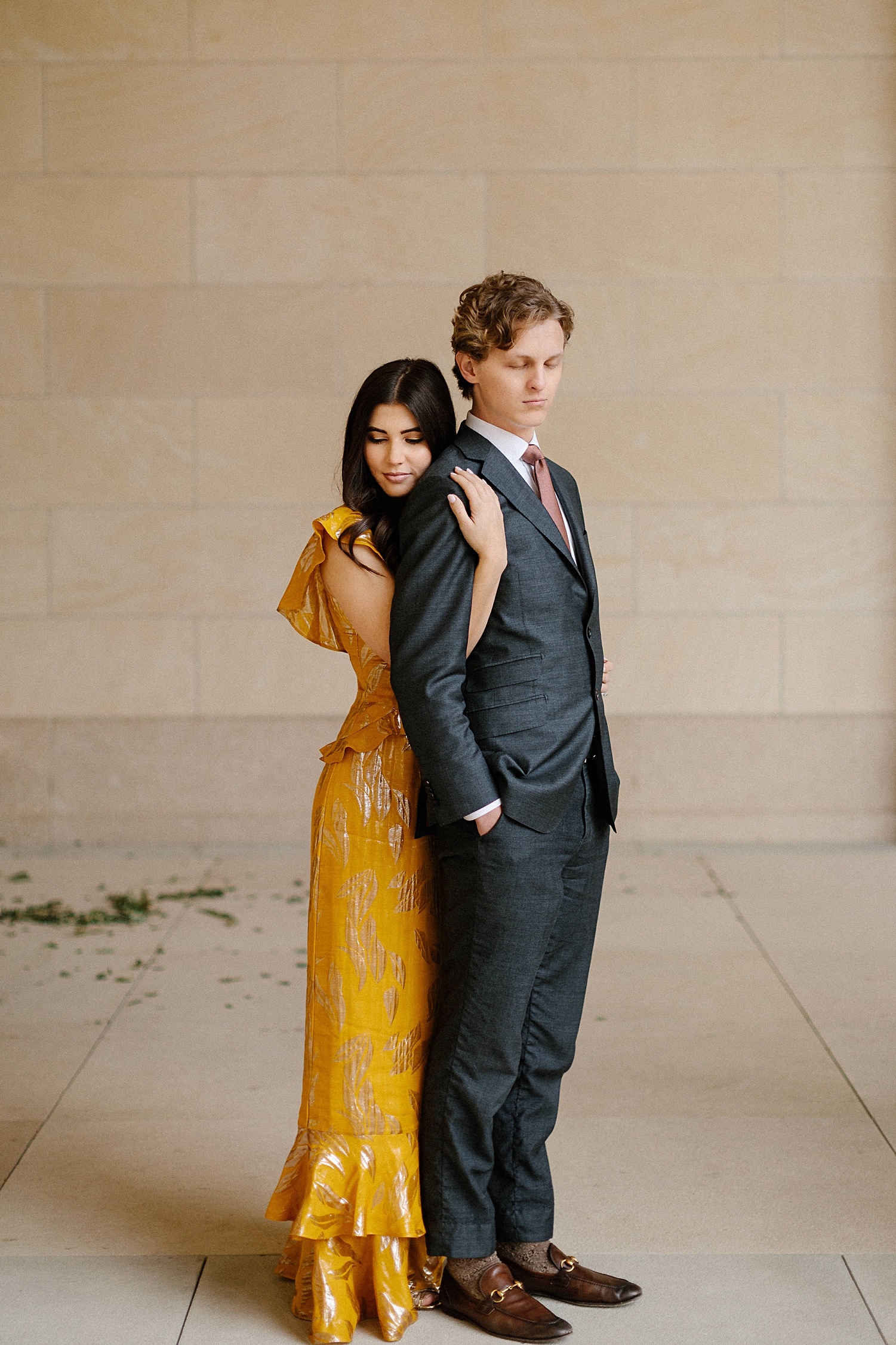 woman in yellow dress hugging man in suit in front of stone wall engagement Dallas