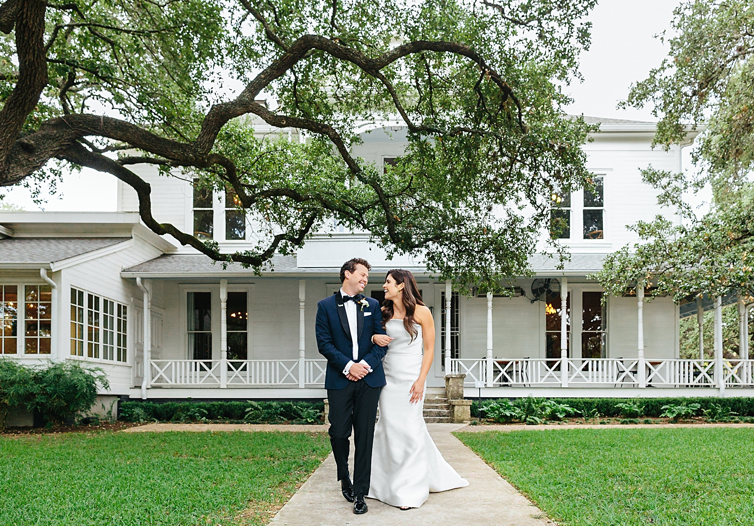 Bride and Groom walking in front of white southern mansion Matties Wedding Austin