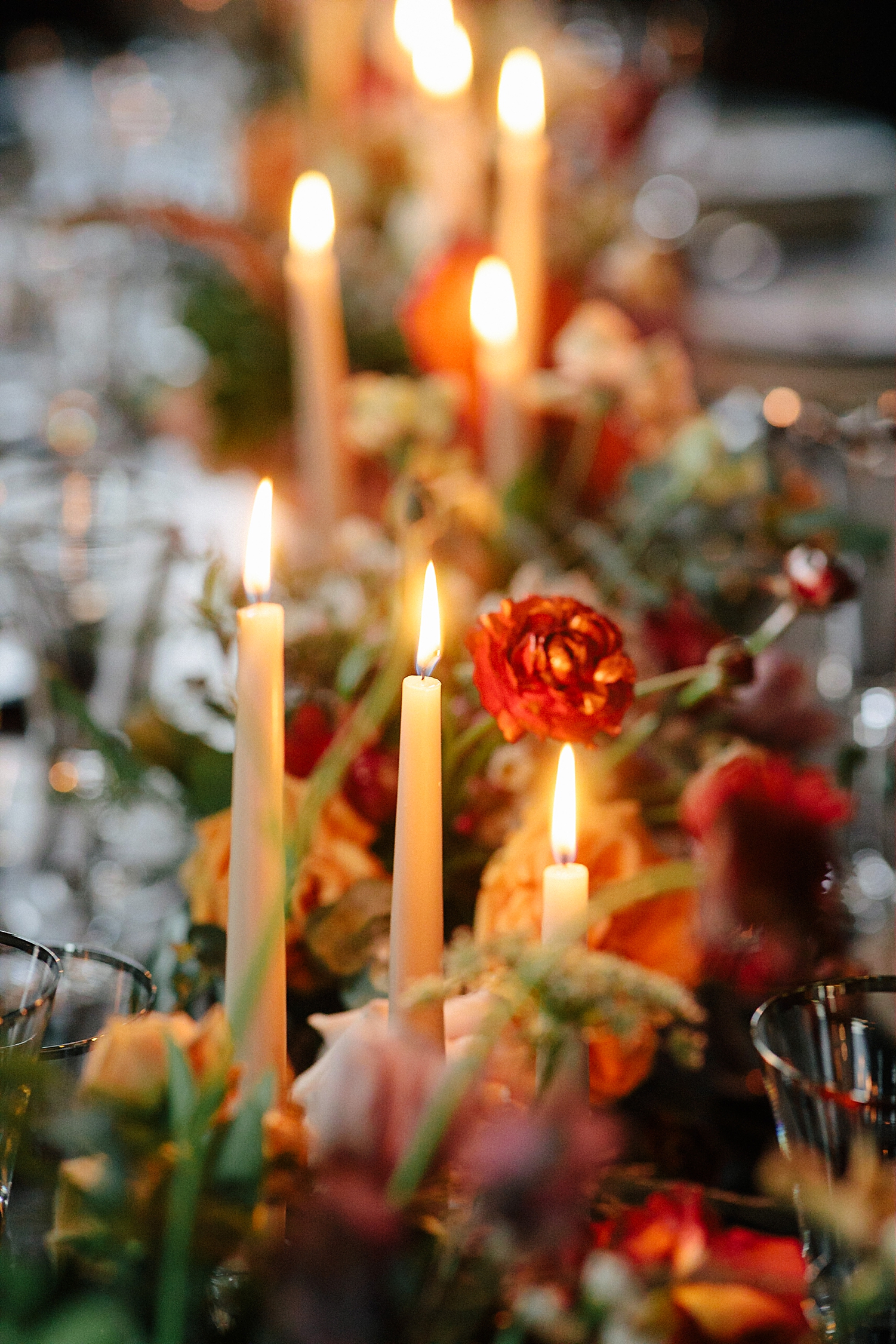 wedding reception table with candles orange, red florals 