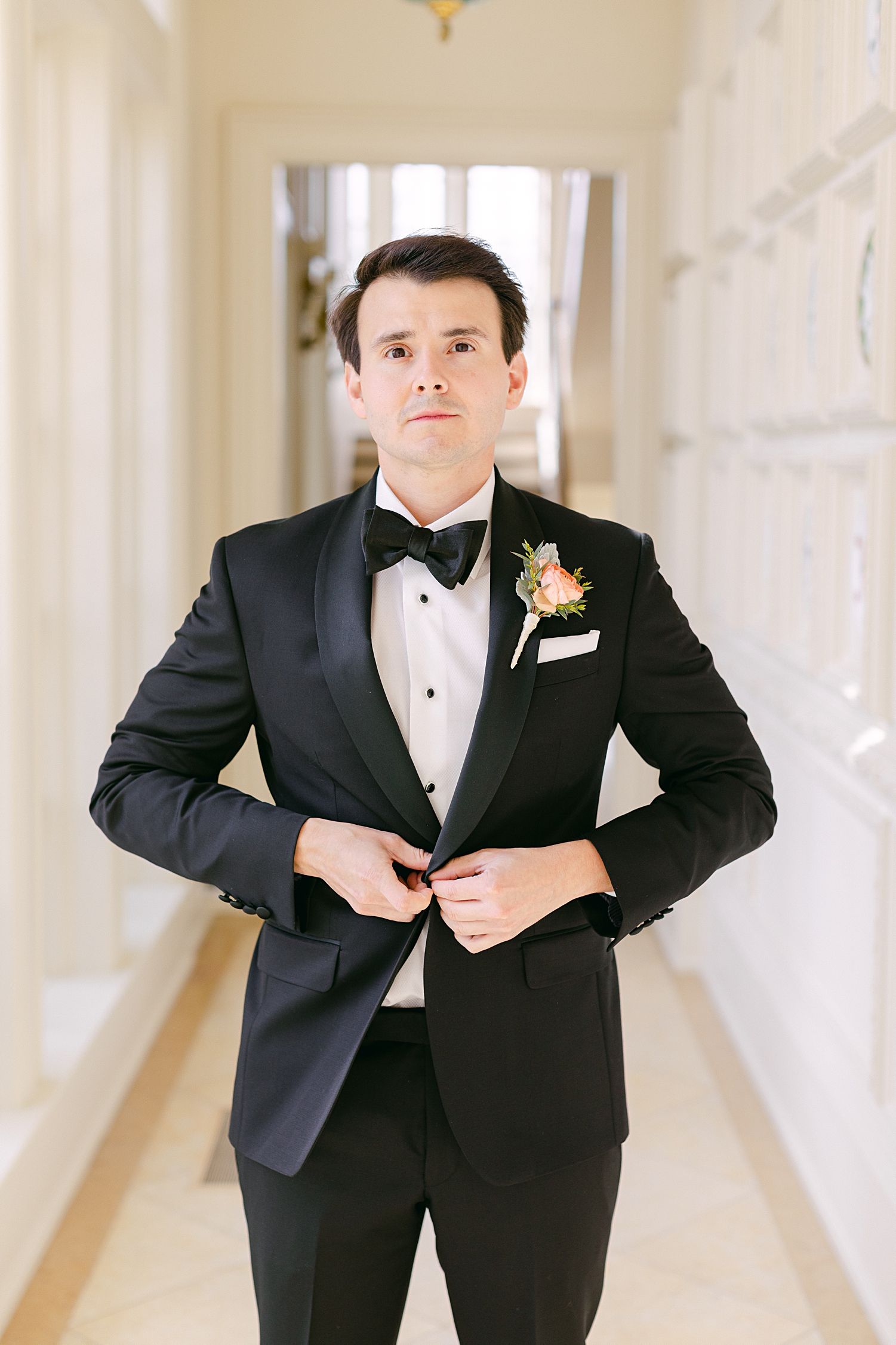 groom in tuxedo buttoning jacket 