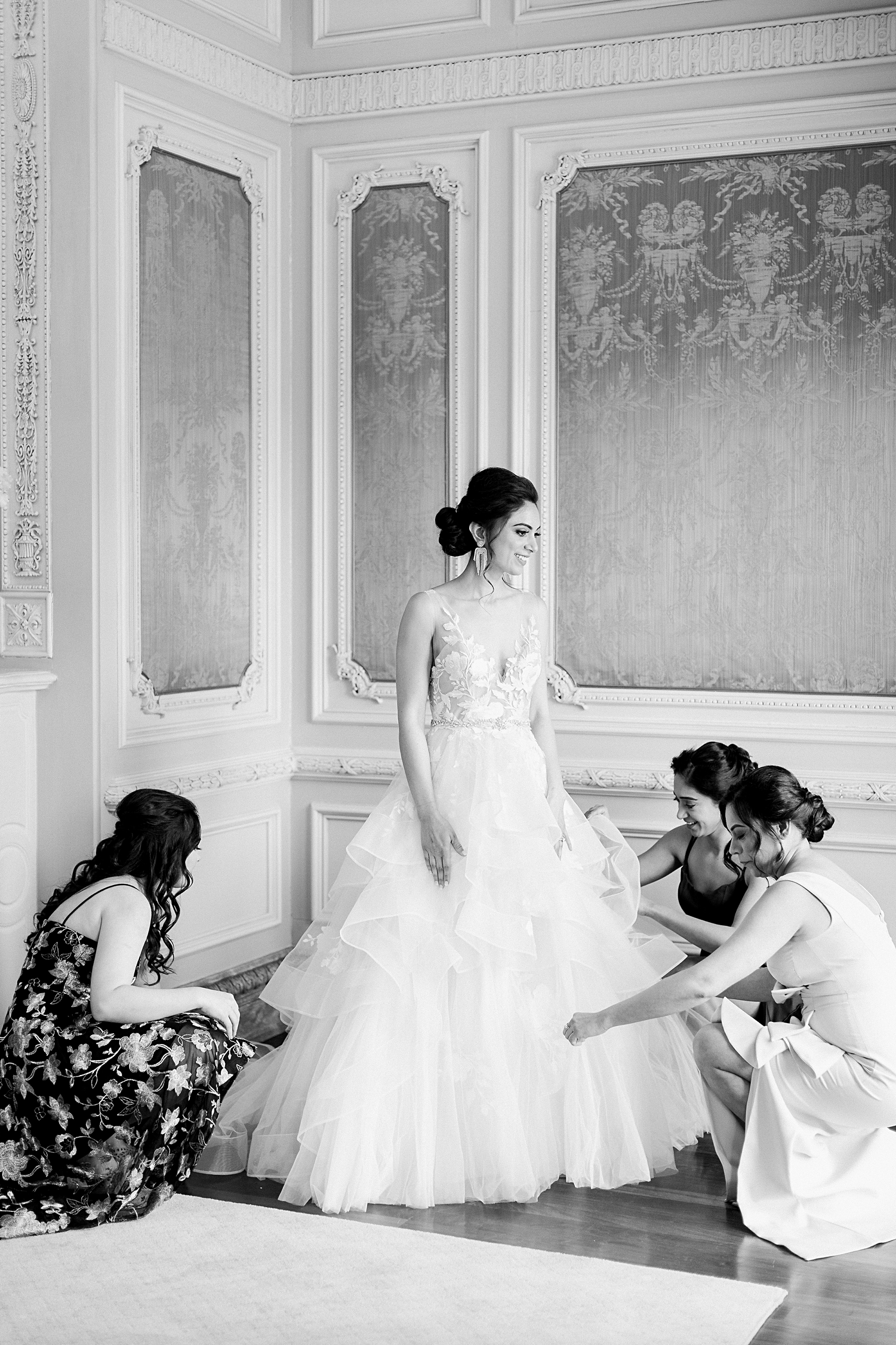 Bride getting help from bridesmaids fluffing wedding dress
