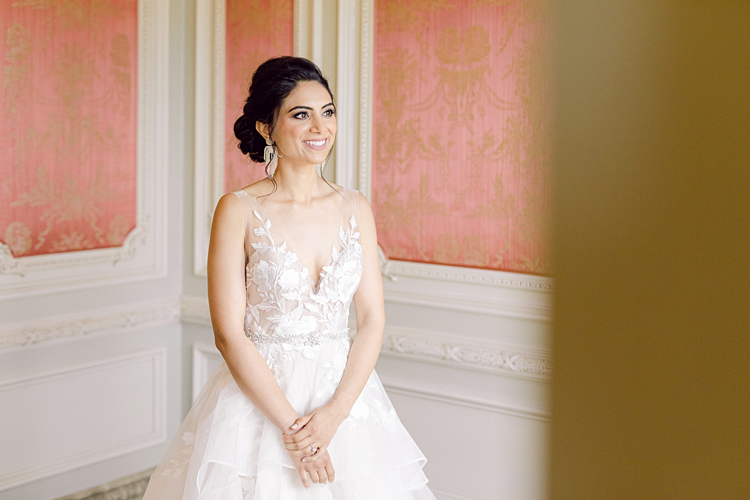 Bride in white dress standing in french estate wedding room smiling