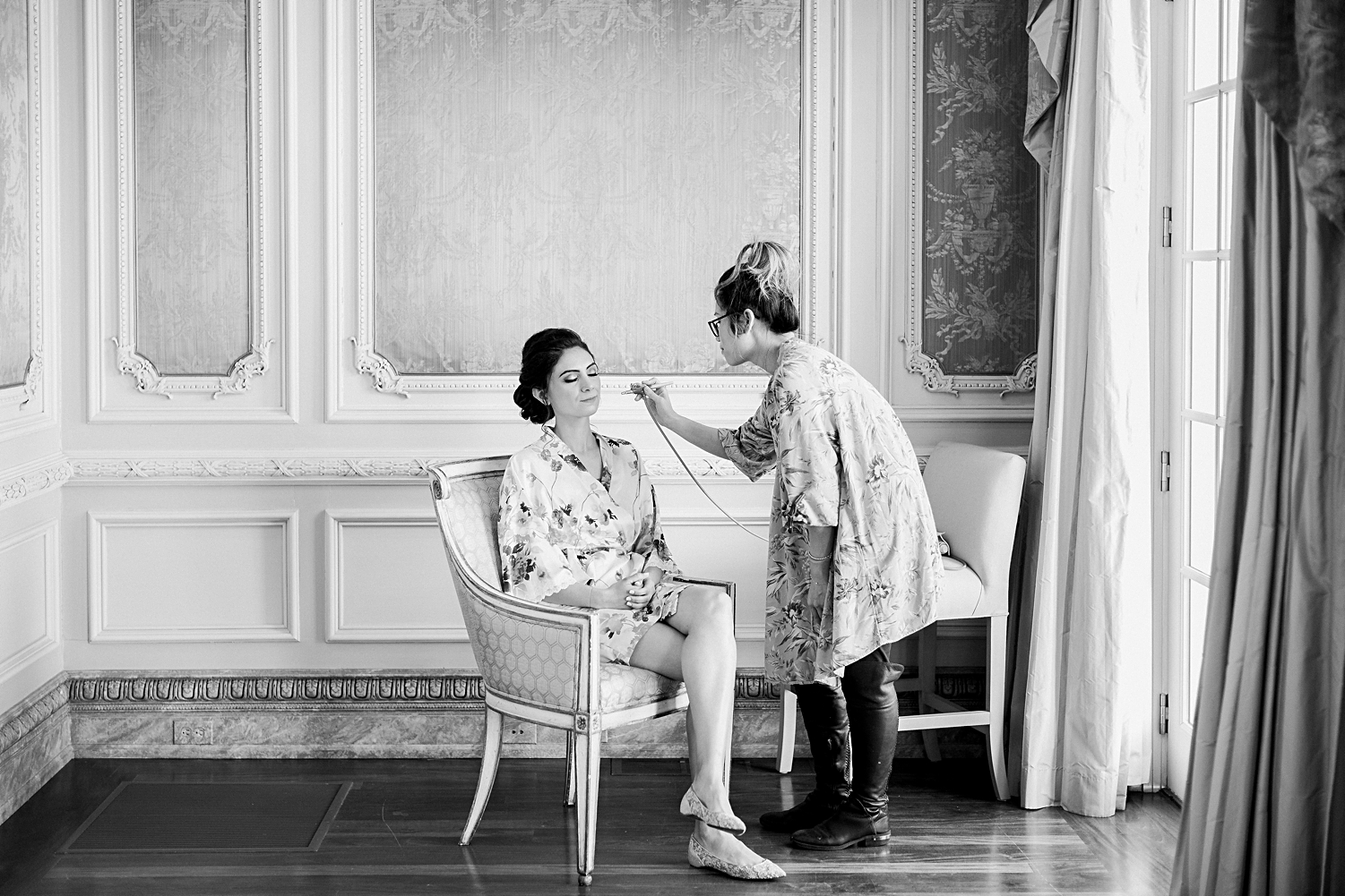bride sitting in chair having makeup done french style room Olana Wedding 