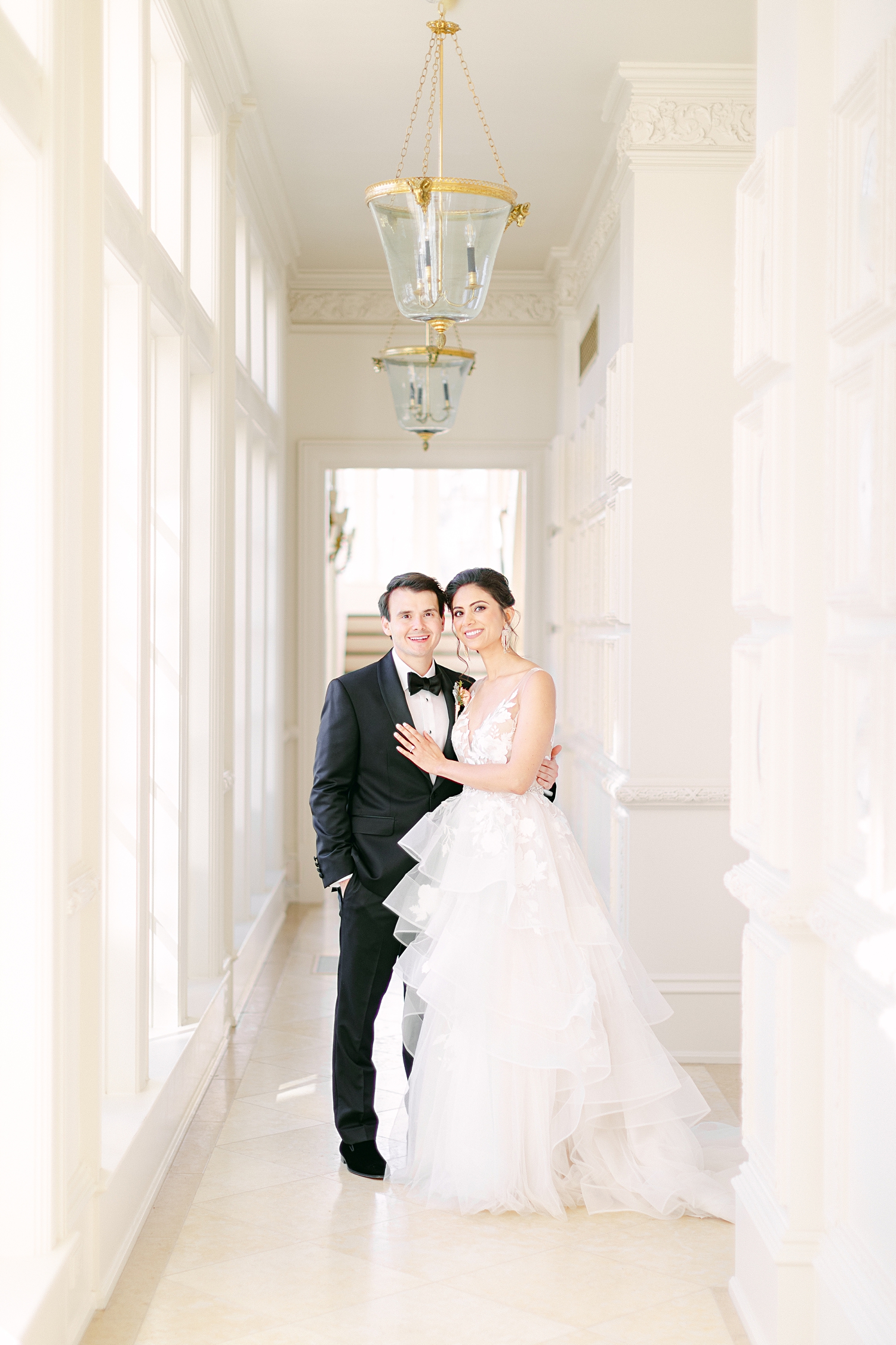 Bride and groom standing in white hallway wedding smiling