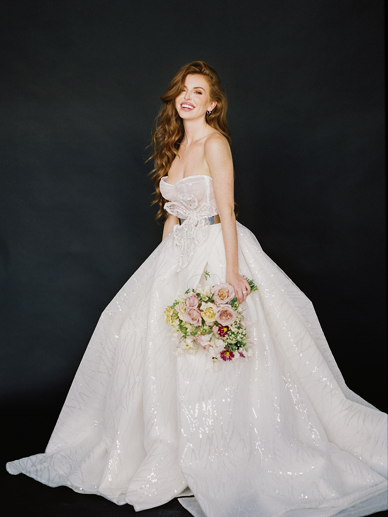 red headed girl in sparkling white wedding gown holding colorful floral bouquet