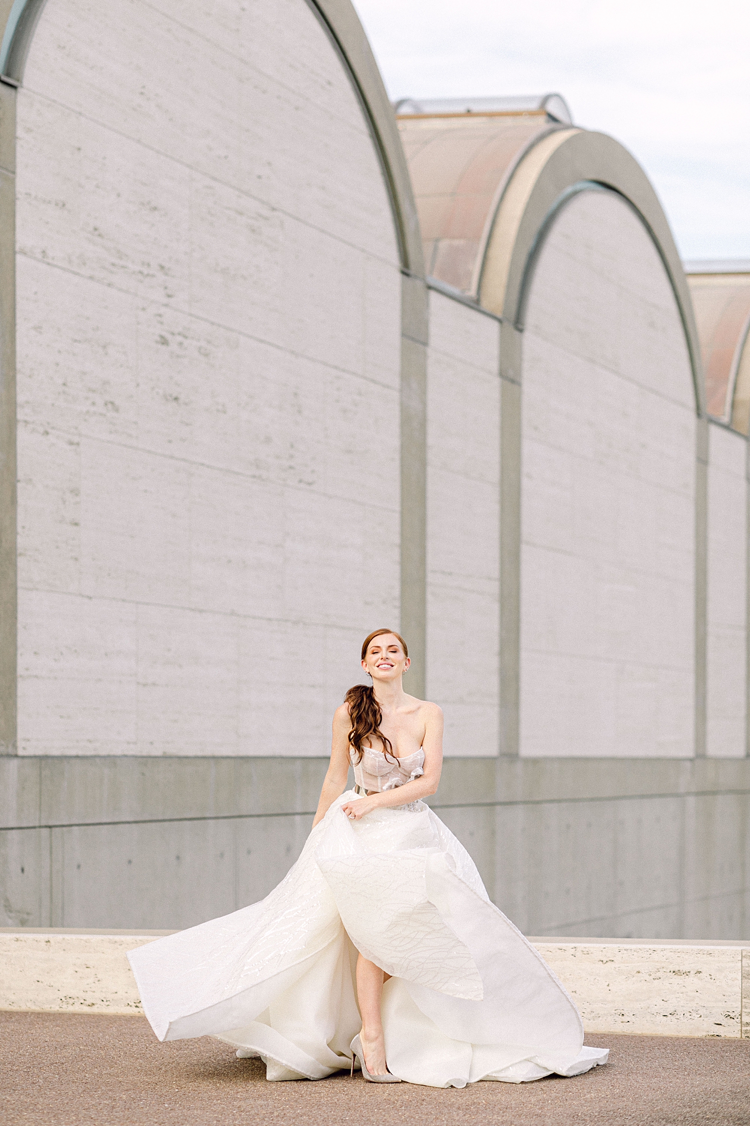 red headed bride in sparkling white Galia Lahav bridal gown smiling in front of architecture