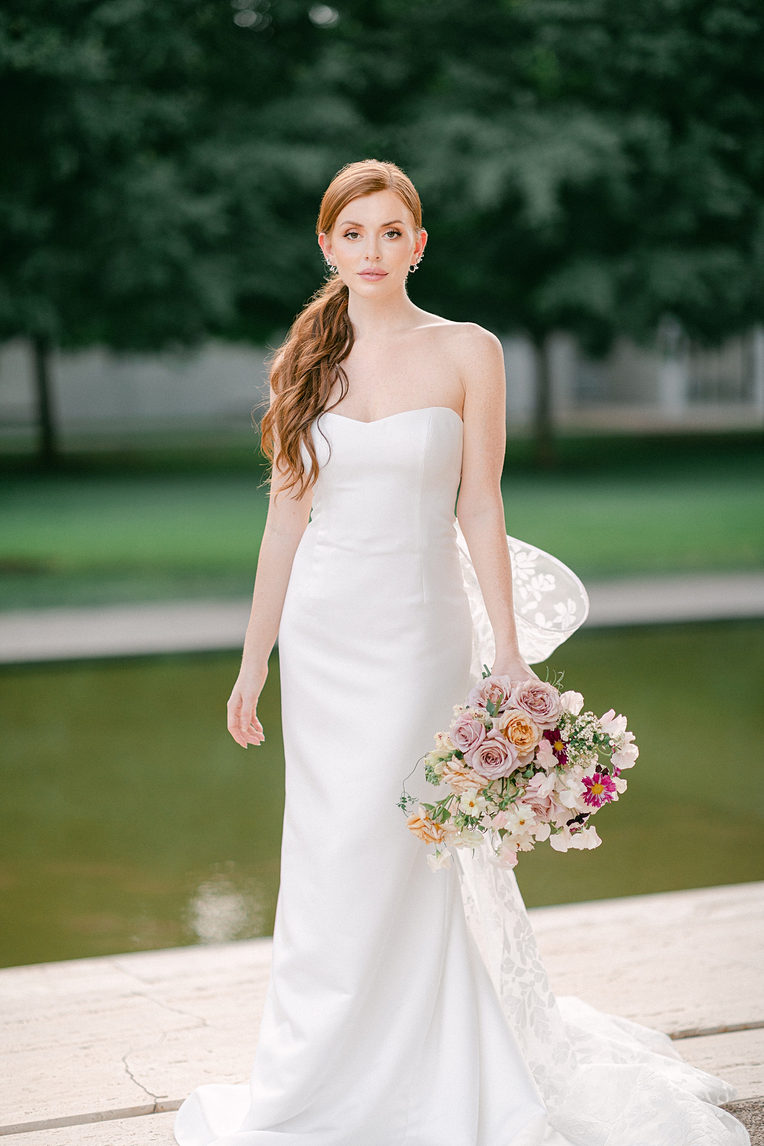 red headed girl in white wedding gown holding colorful floral bouquet